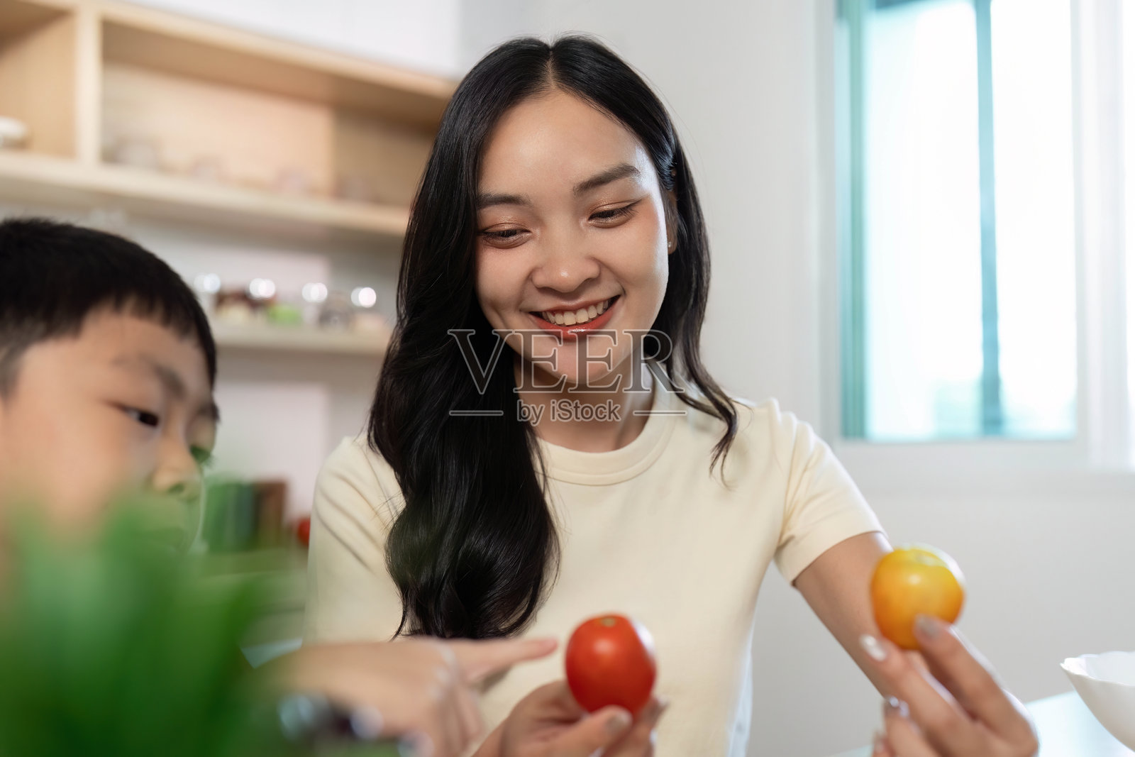 健康烹饪。母亲和儿子享受着与新鲜食材一起的有趣烹饪时光。照片摄影图片