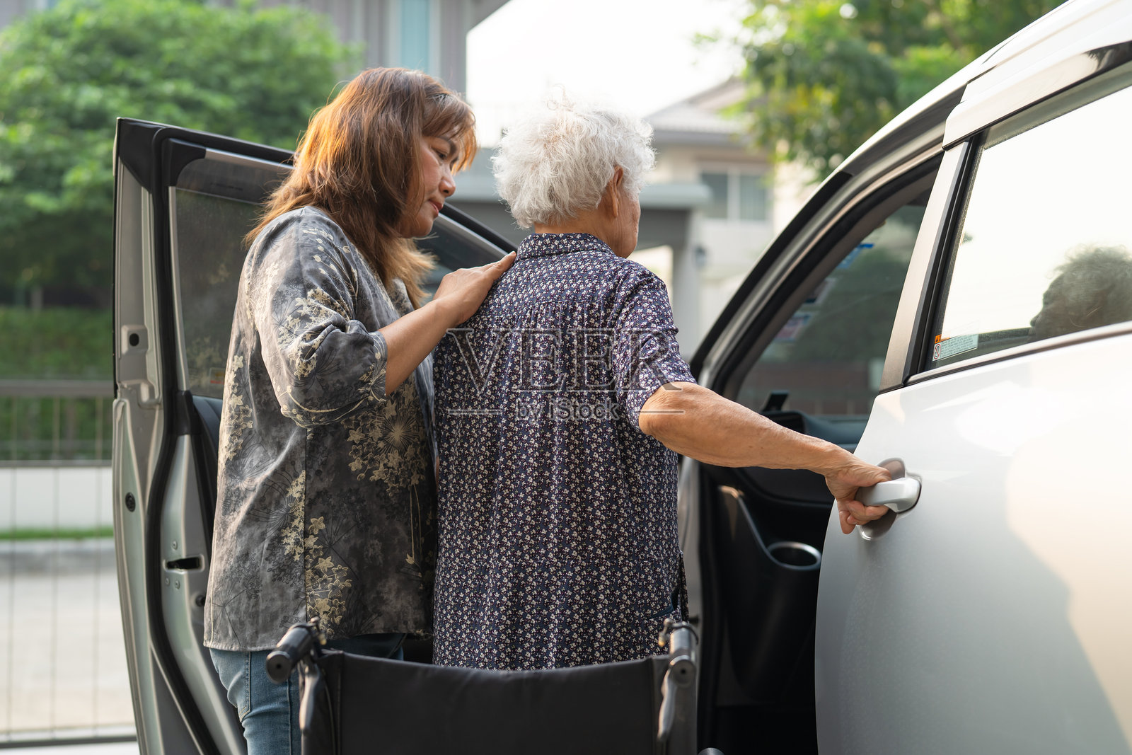 护理人员帮助亚洲老年女性残疾患者上车。照片摄影图片