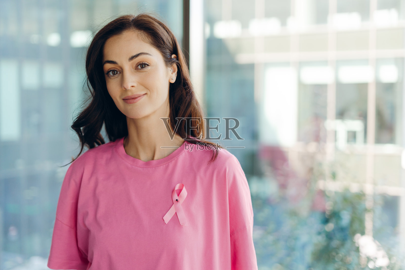 女性佩戴粉色丝带，支持乳腺癌意识月。照片摄影图片