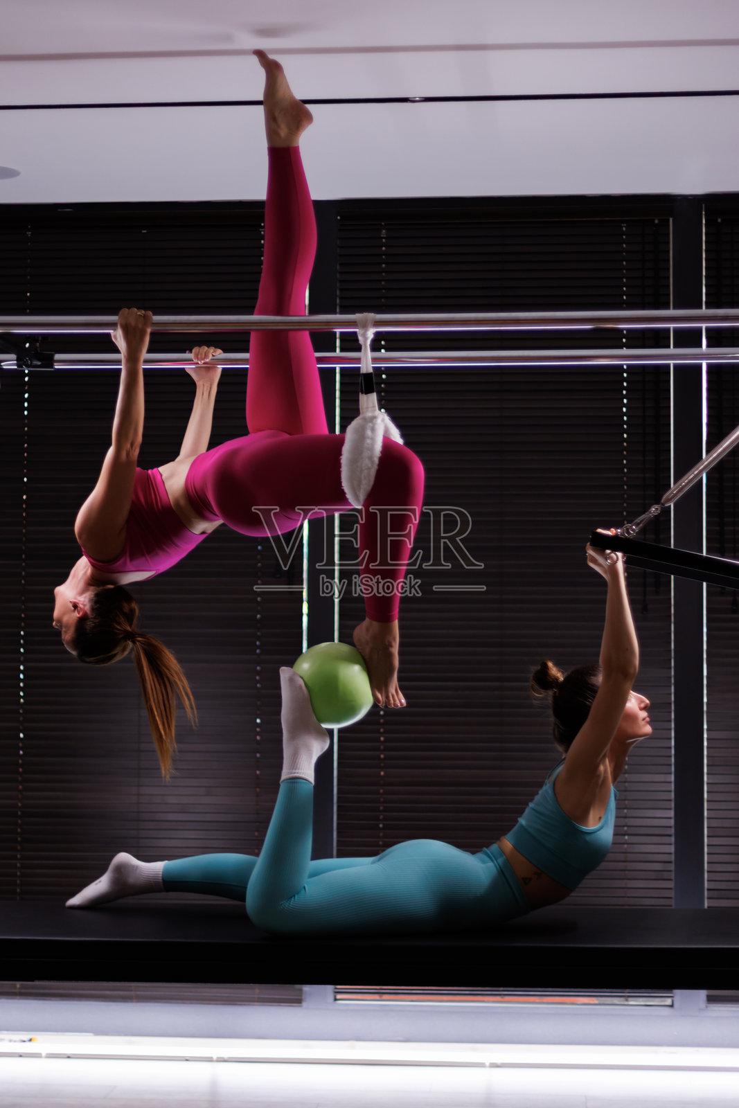 女性在现代健身房进行空中健身训练，提升力量和柔韧性，白天的课程。照片摄影图片