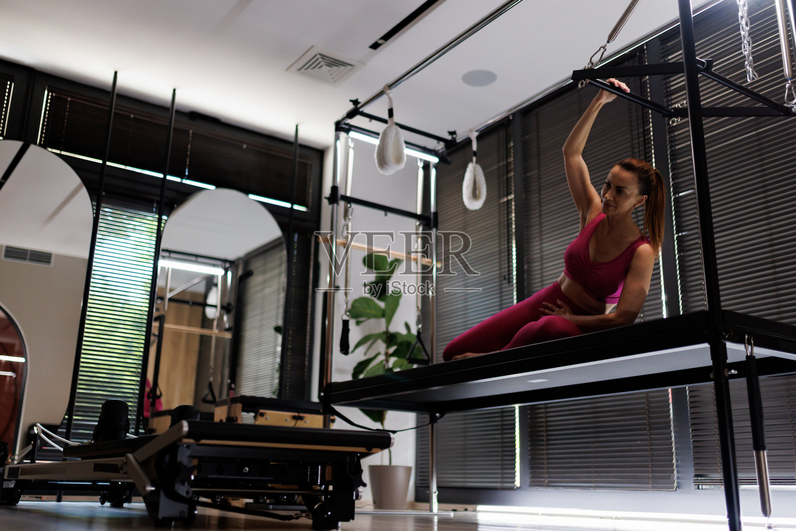 女性在现代健身工作室的普拉提器械上练习，进行早晨锻炼以增强力量和灵活性。照片摄影图片
