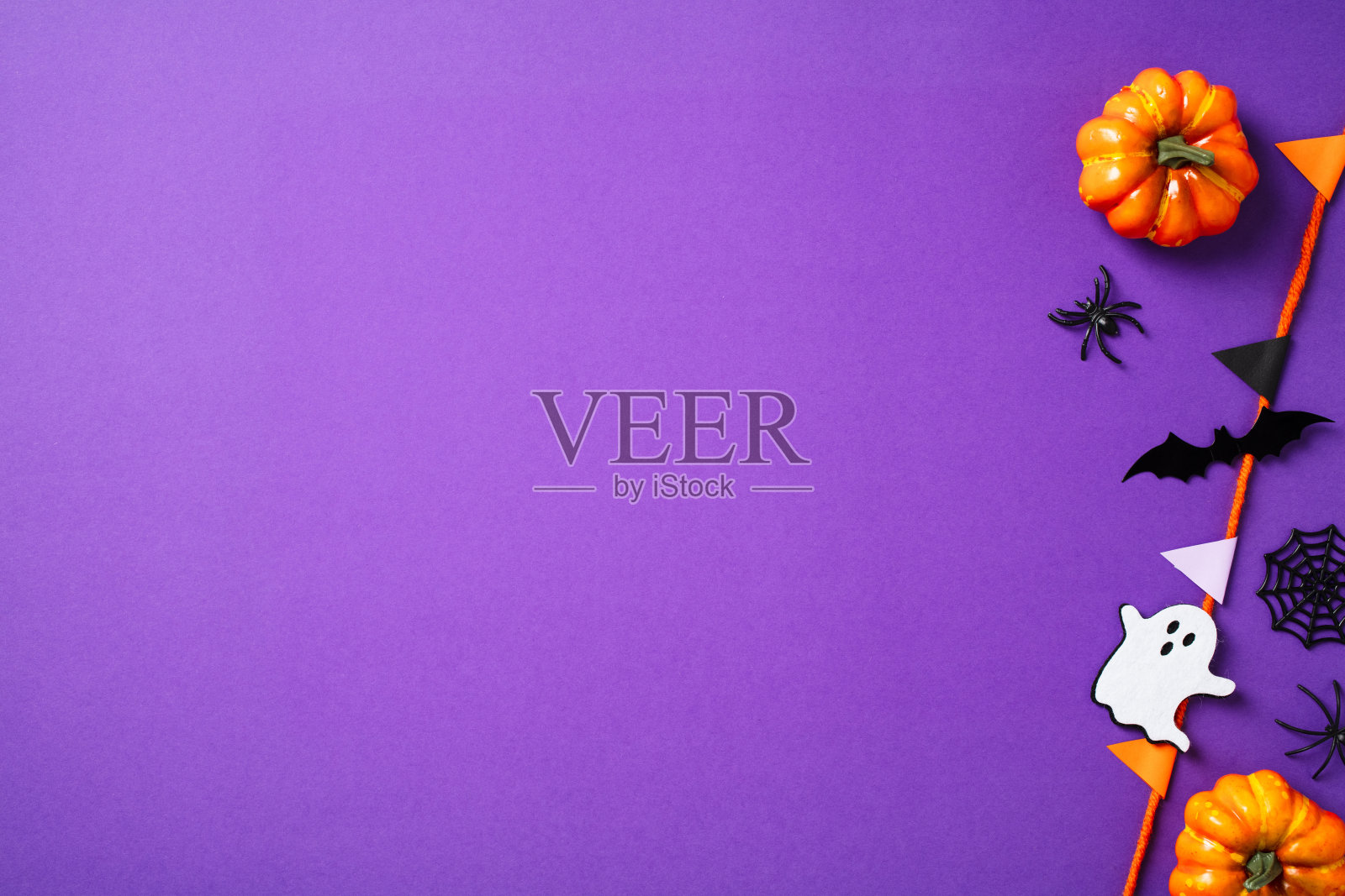 万圣节派对装饰，南瓜、蜘蛛、鬼魂，紫色背景上的彩旗花环。快乐的万圣节概念。照片摄影图片