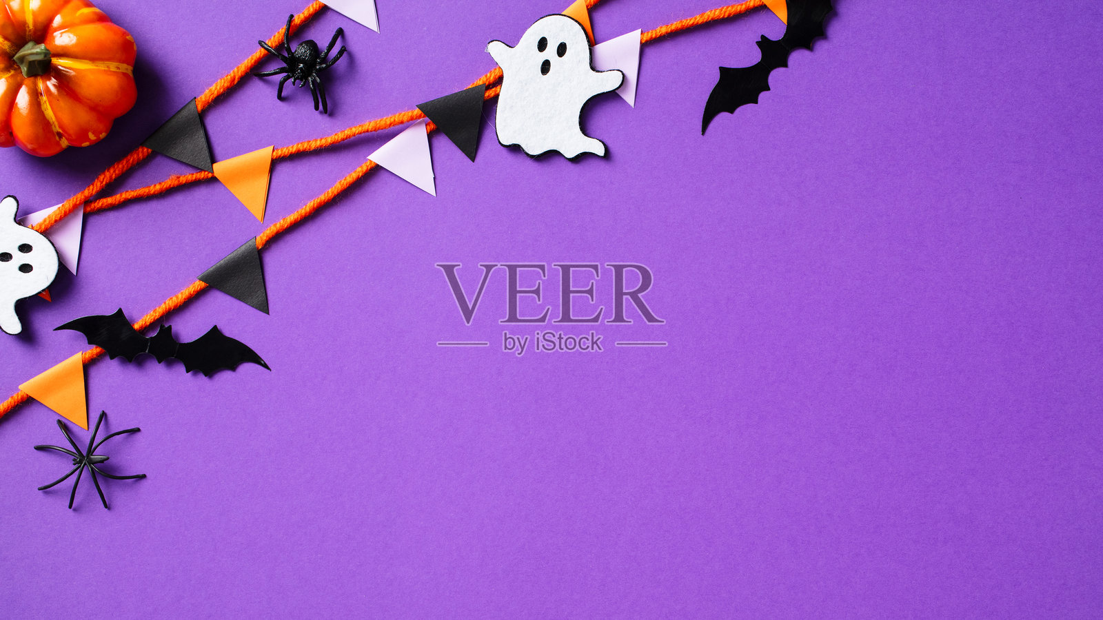万圣节快乐概念。万圣节派对装饰，南瓜、鬼魂、蝙蝠、蜘蛛和彩旗在紫色背景上。平铺，俯视，留白空间。照片摄影图片