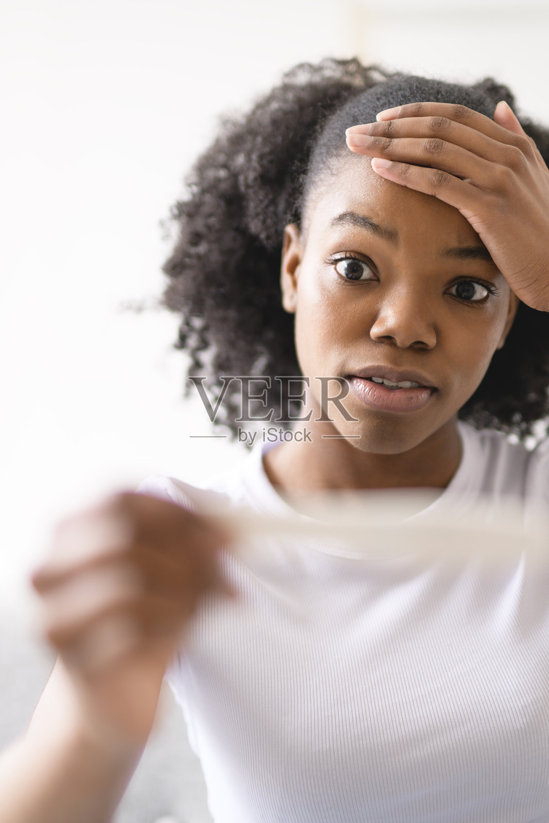 黑人女性，坐在家中的沙发上，怀孕测试，神情困惑、紧张，等待结果。照片摄影图片