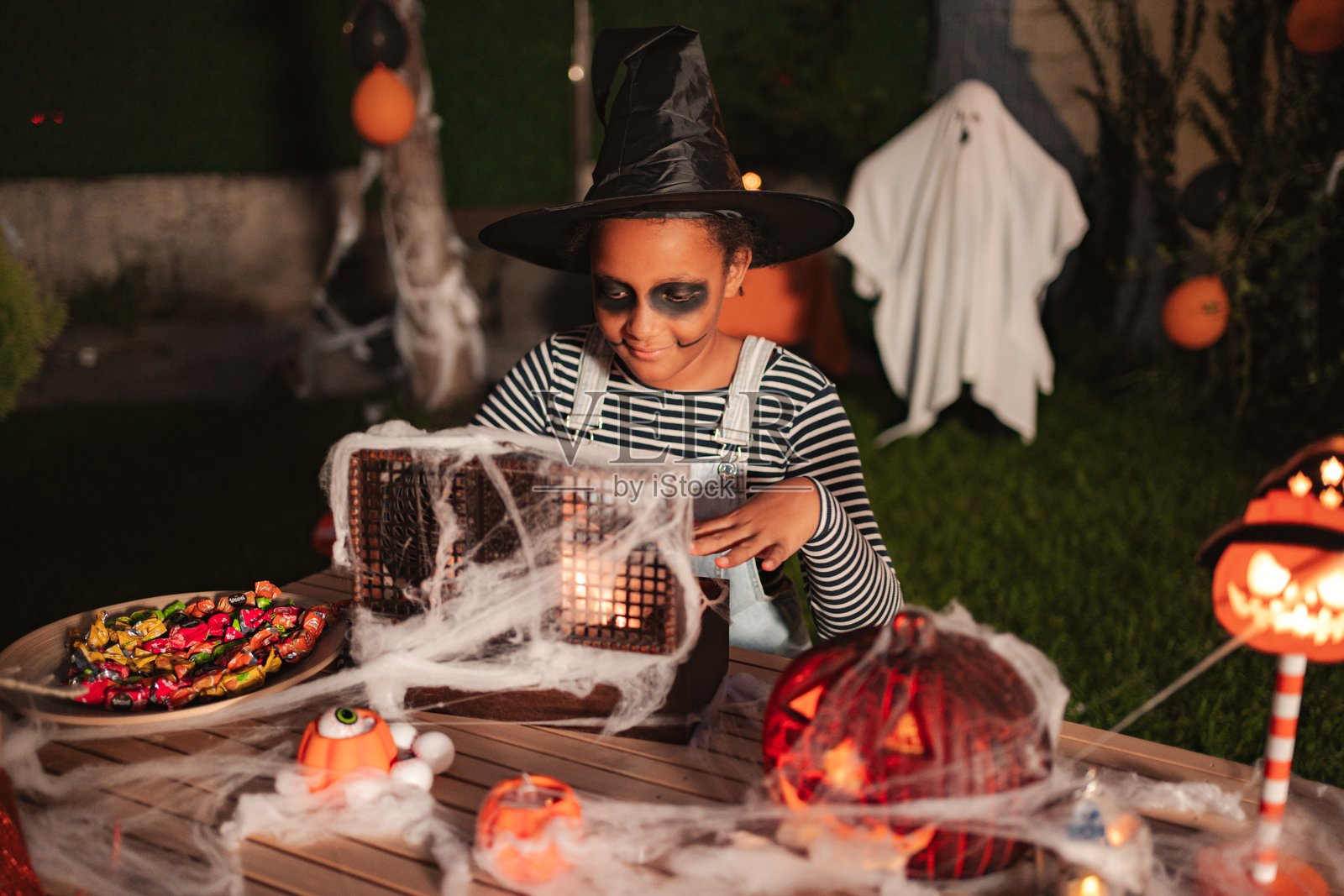 小女巫在夜晚准备万圣节装饰和糖果照片摄影图片