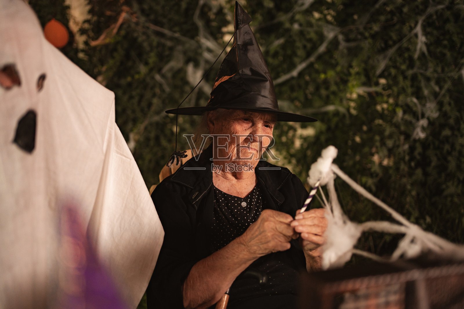 一位戴着女巫帽的老年女性正在制作万圣节装饰品照片摄影图片