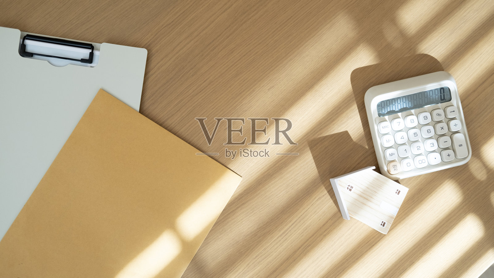 房屋模型和计算器与棕色文件夹放在木桌上，代表住房金融抵押贷款计算、物业规划和投资安全。照片摄影图片