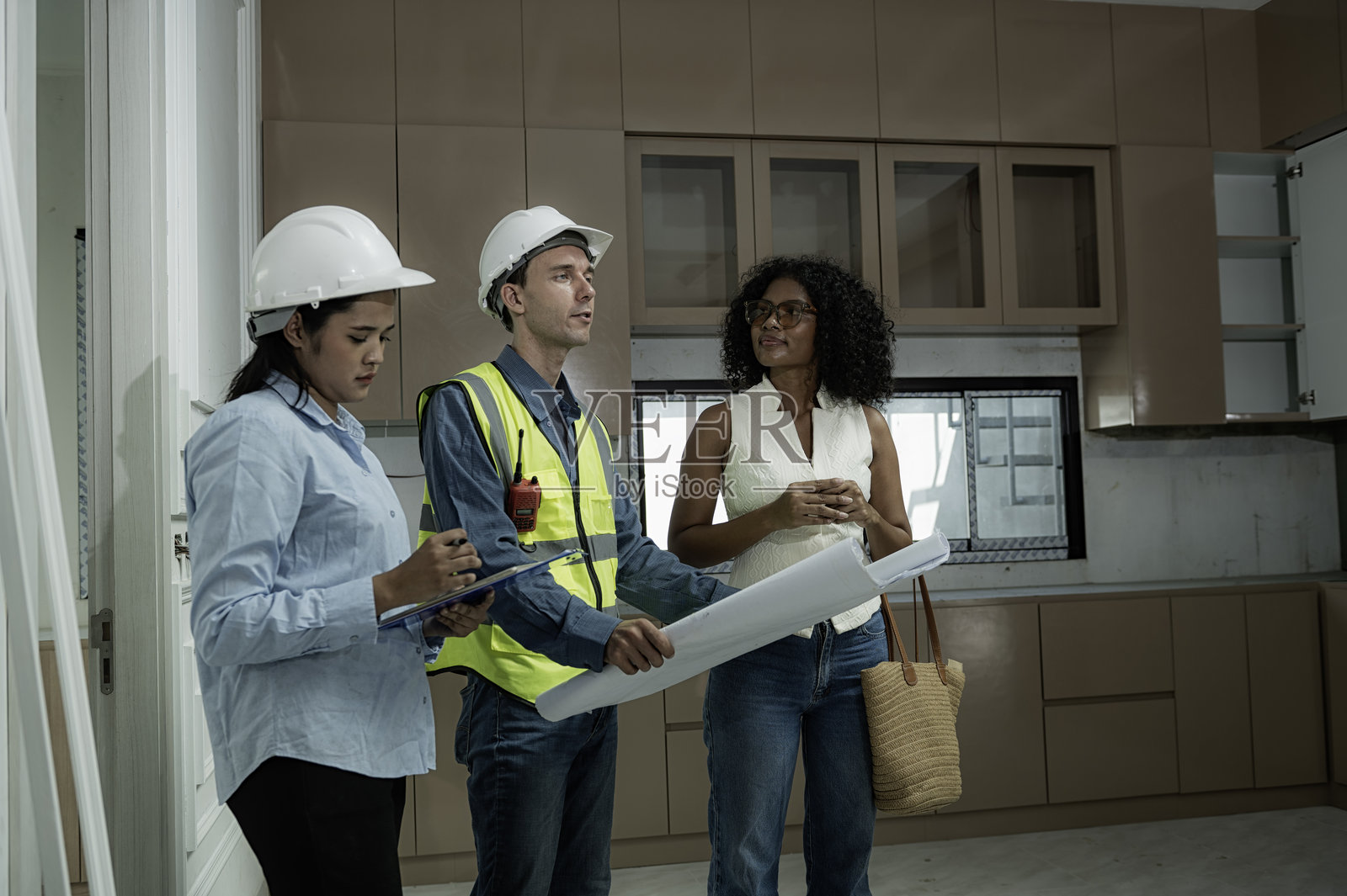 工程团队和客户在现代厨房内审查建筑计划。照片摄影图片