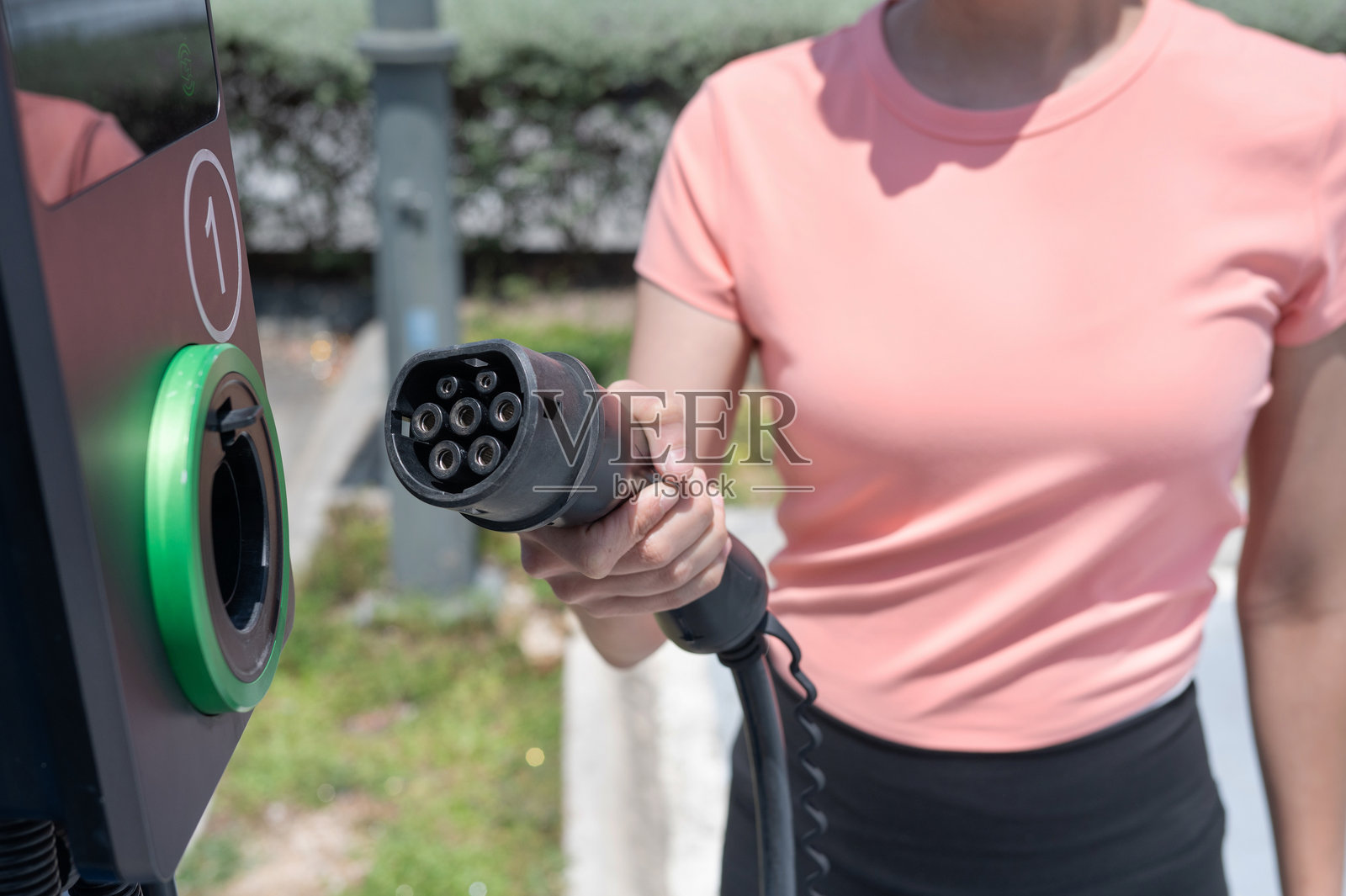 环保生活方式：女性手持电动车充电器照片摄影图片