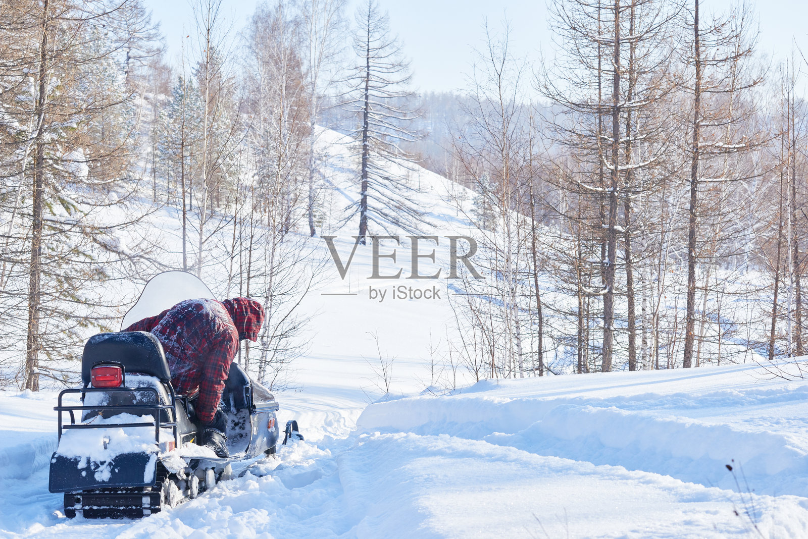 男子骑着雪地摩托穿越冬季森林风景照片摄影图片