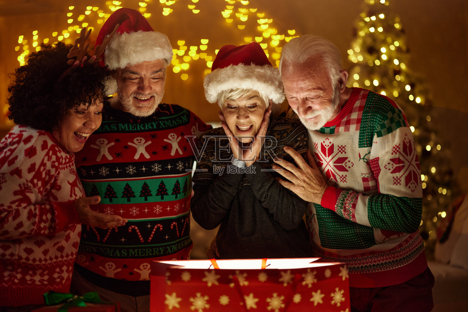 惊讶的老年朋友们在家里查看圣诞礼物。照片摄影图片