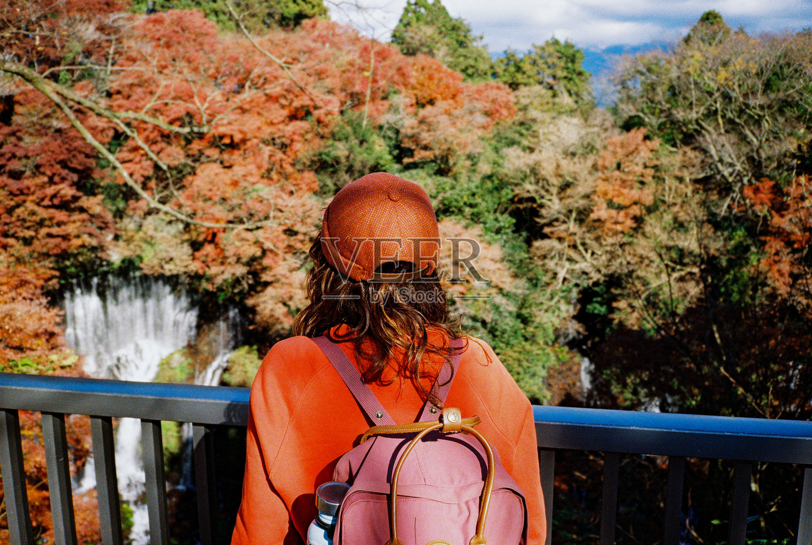 女子在富士河口湖附近的秋季森林中凝视瀑布照片摄影图片