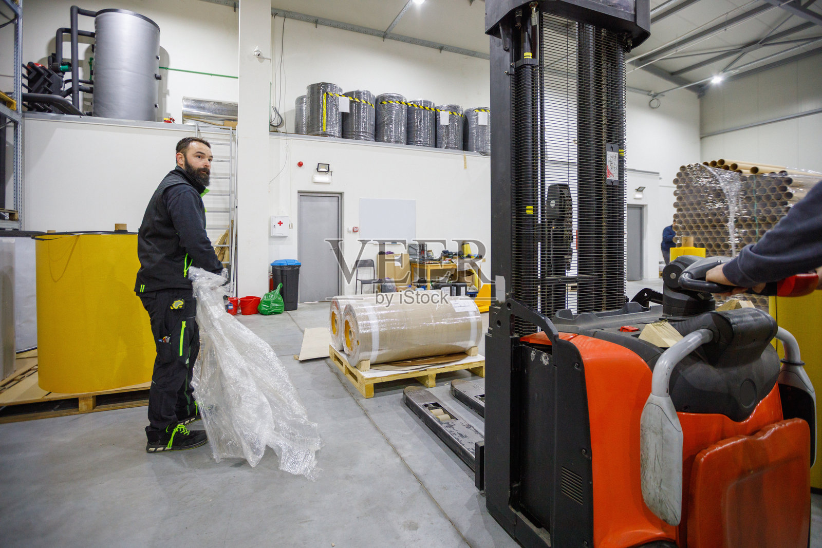 工业仓库场景，叉车操作员在生产设施中包裹气泡膜照片摄影图片