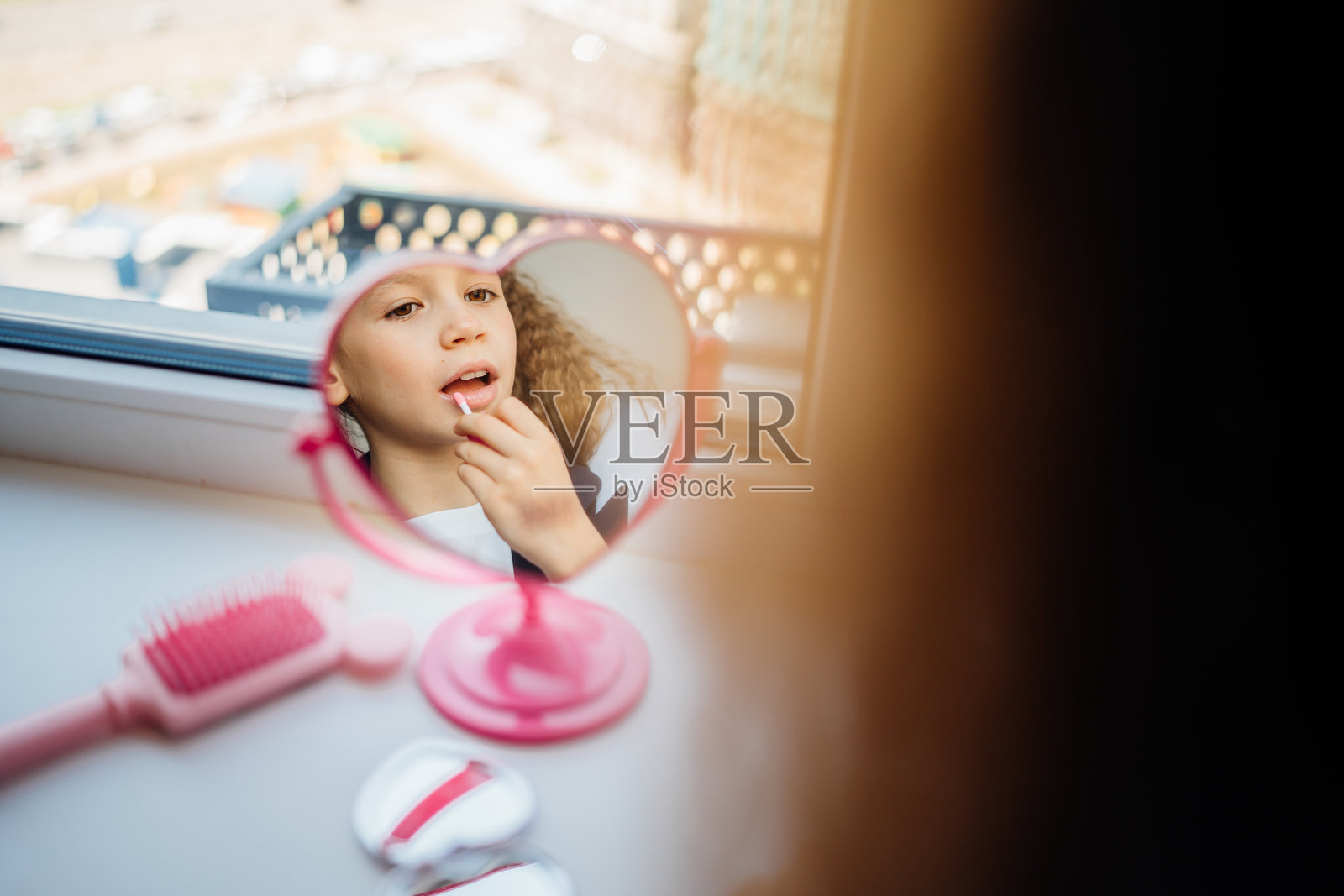 小女孩在心形镜子前涂抹唇彩照片摄影图片