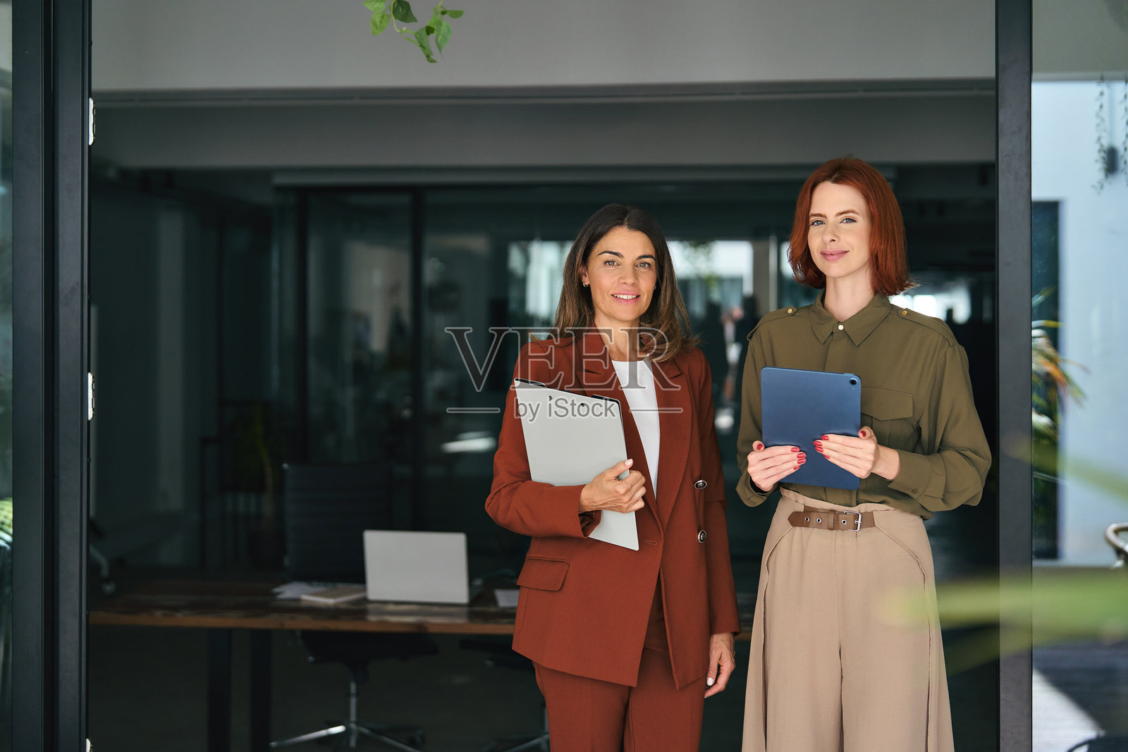 两位快乐微笑的女商人在办公室工作，肖像。照片摄影图片