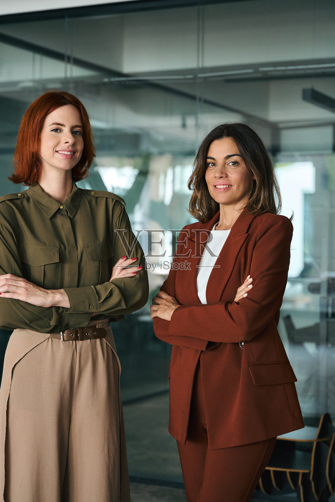 两位微笑自信的女商人在办公室交叉双臂，肖像。照片摄影图片