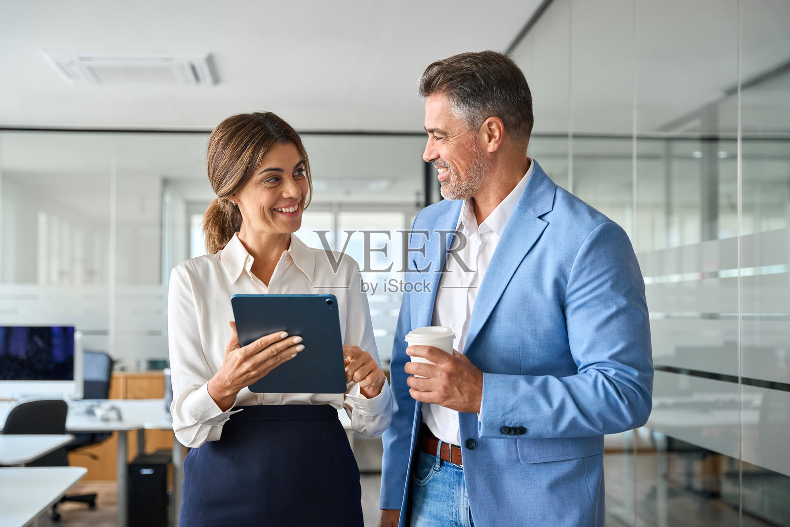 两位快乐的商务高管在办公室使用平板电脑。照片摄影图片