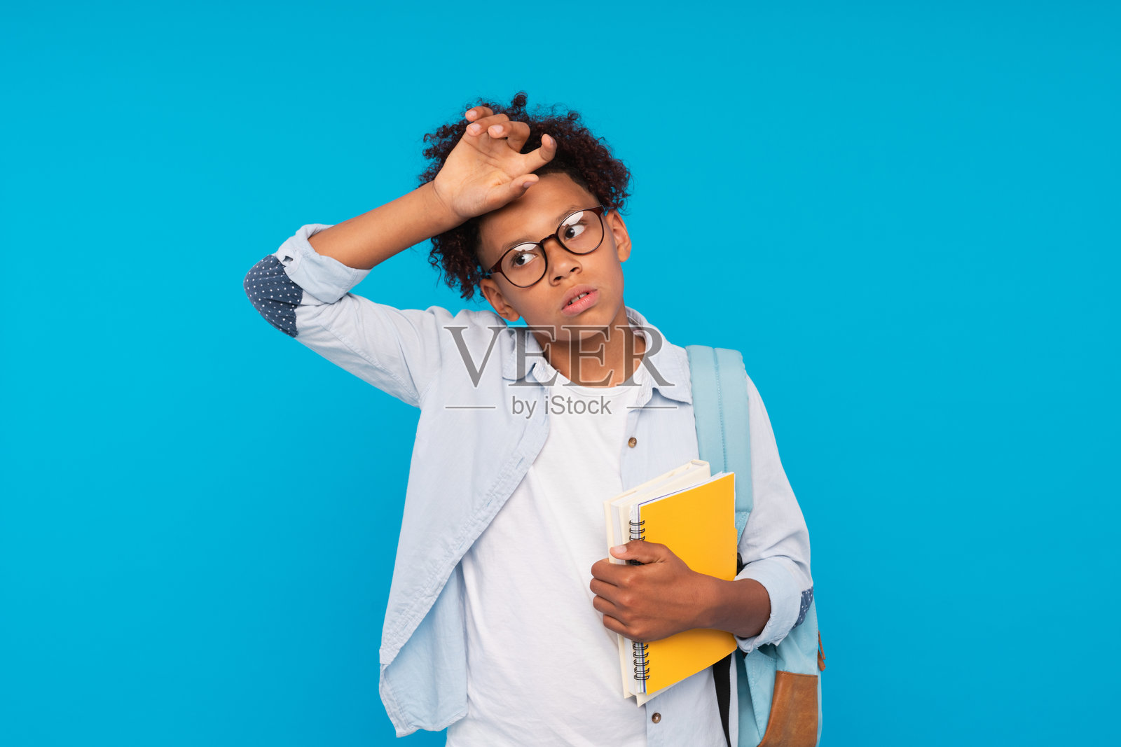 伤心不快乐的非裔美国男孩，戴着时尚眼镜，面露痛苦，手捂额头，因摔倒而感到不适。沮丧的深肤色孩子正在忍受剧烈的头痛。照片摄影图片