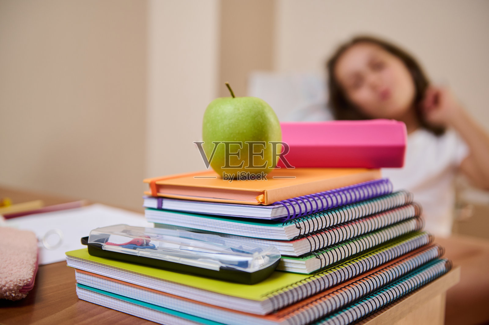 绿色苹果静静地放在堆叠的笔记本上，营造出学习环境。照片摄影图片