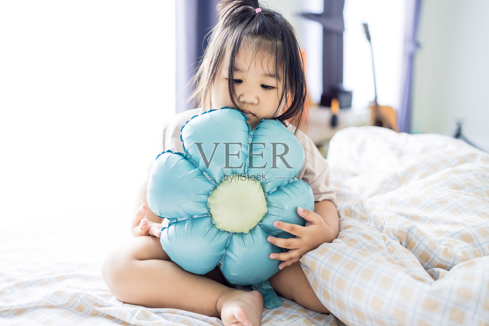 可爱的小女孩在床上玩玩具，快乐地在卧室里玩耍。照片摄影图片