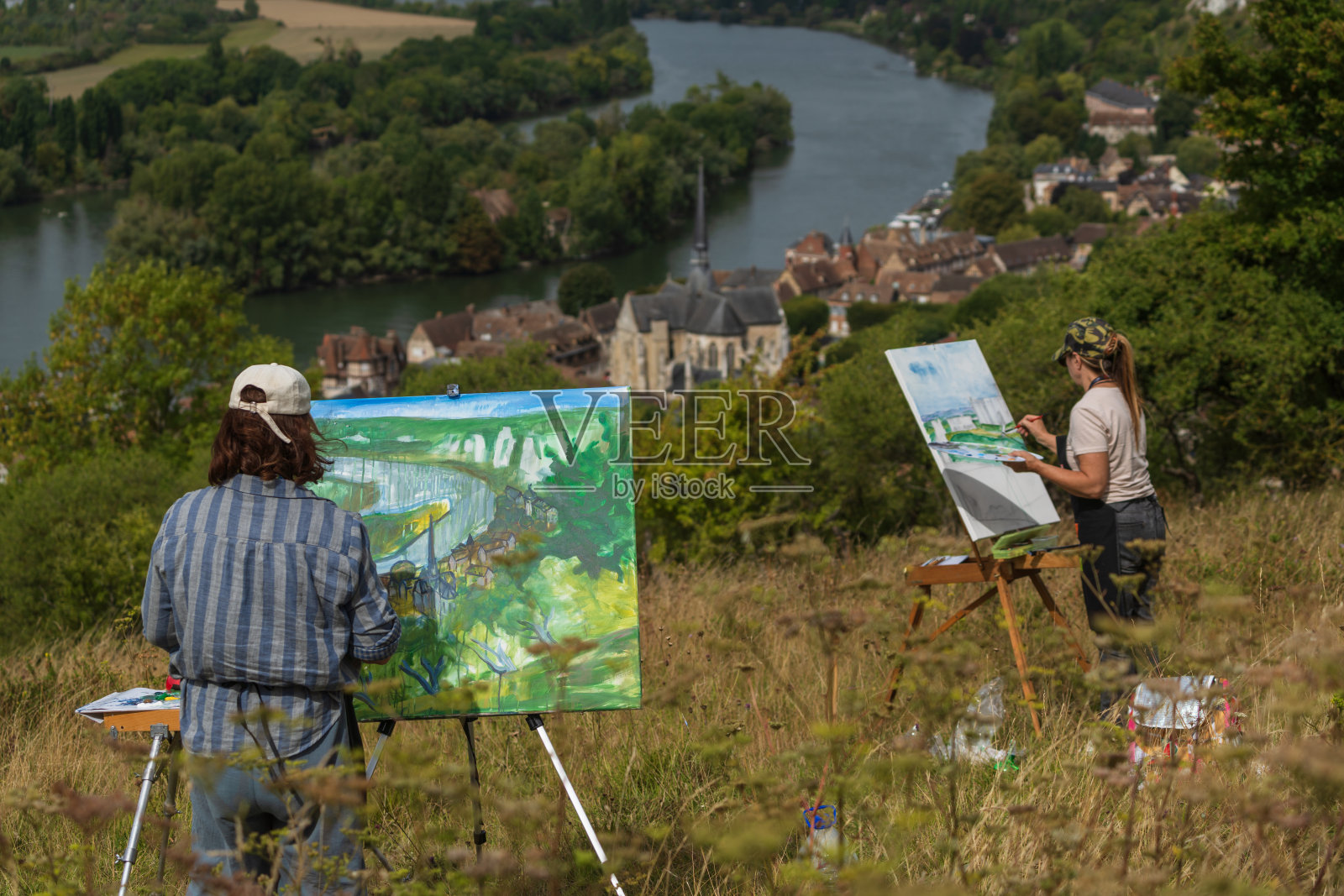 两位艺术家在法国诺曼底的塞纳河畔画风景，背景是莱昂德利。照片摄影图片