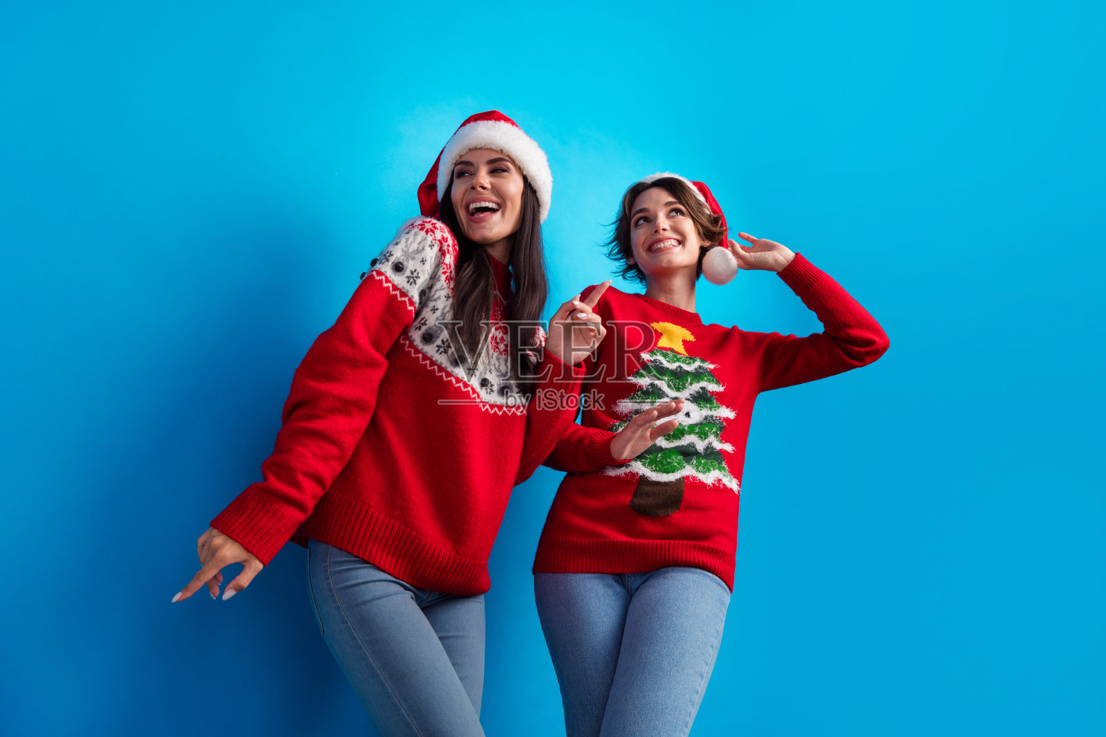 快乐女孩在圣诞派对上跳舞的照片，低角度拍摄，背景为蓝色。照片摄影图片