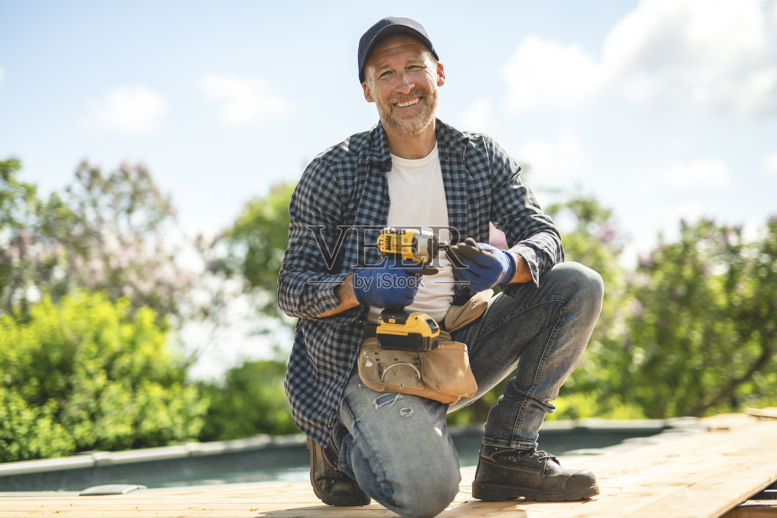 工人正在泳池旁的露台上安装地板。照片摄影图片