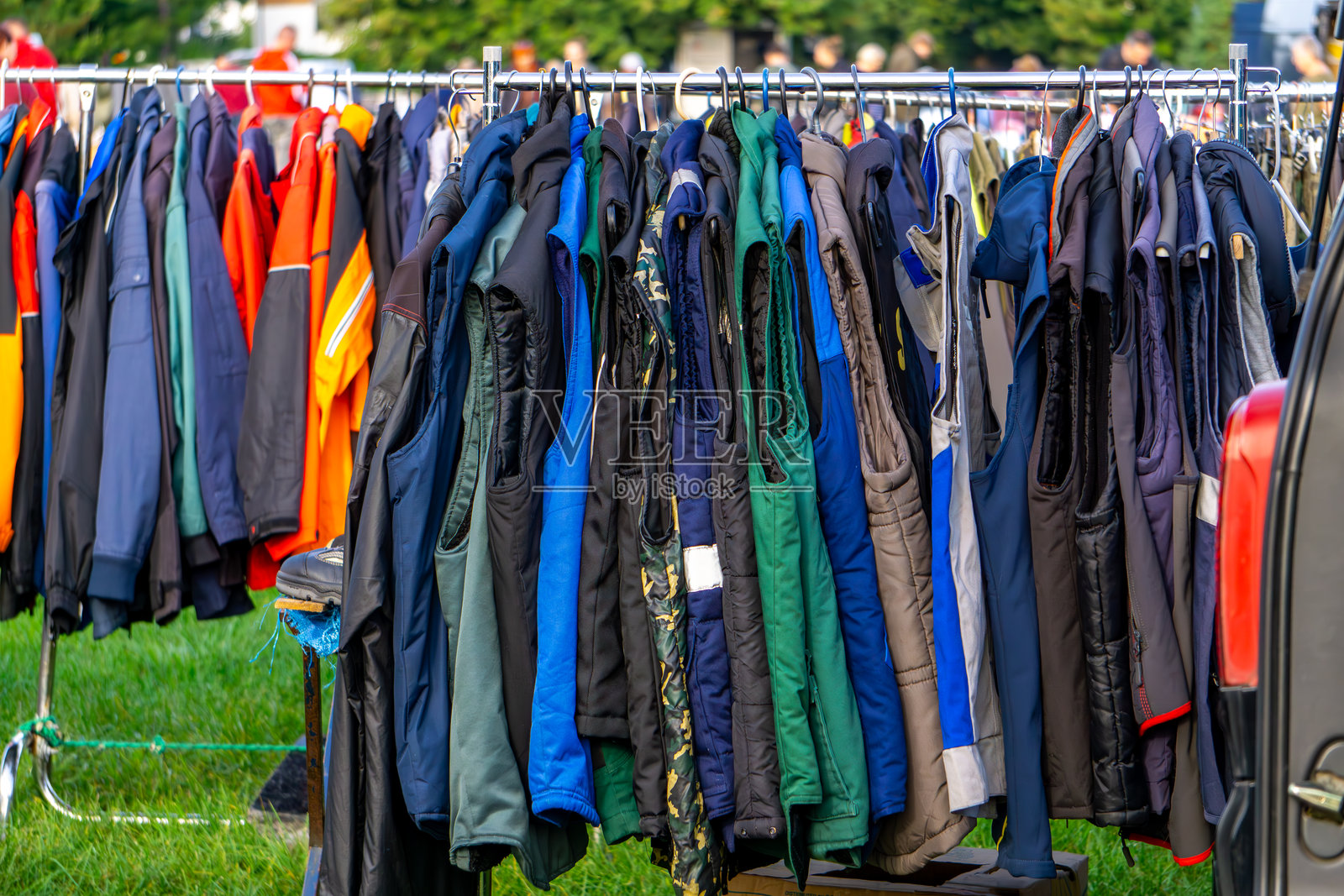 古董跳蚤市场，二手衣物陈列在架子上，五彩斑斓的夹克和背心在户外展示。照片摄影图片