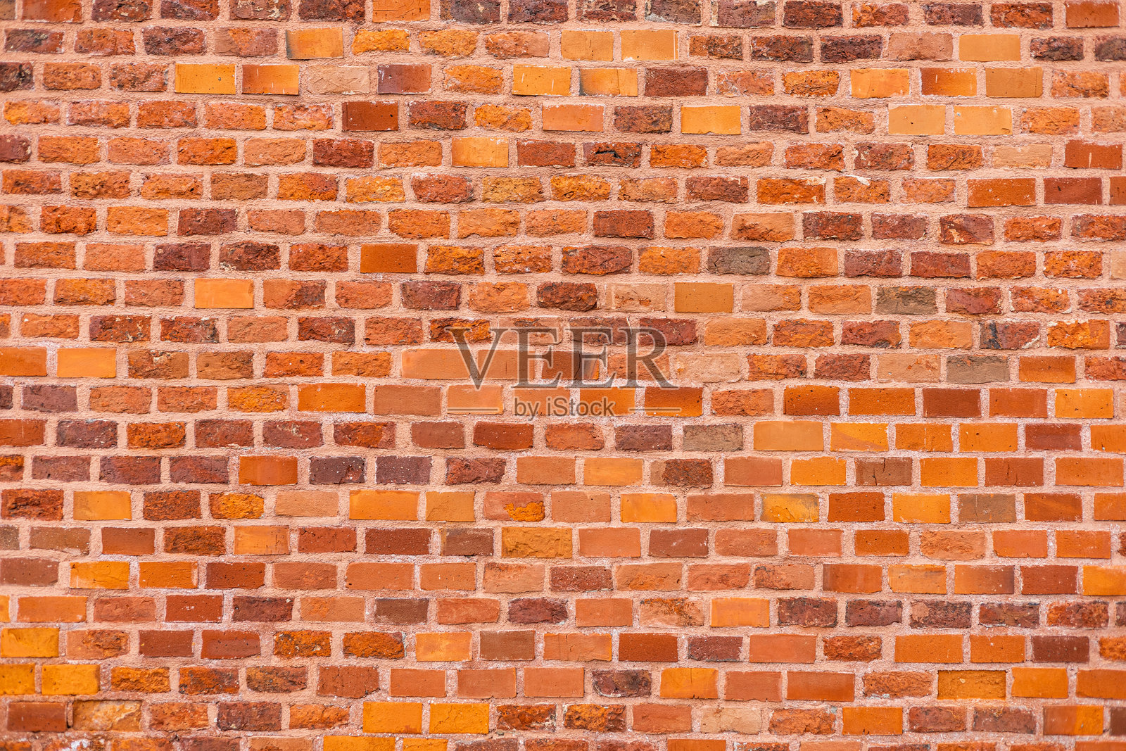 一面纹理丰富的砖墙特写。墙面由橙色和棕色砖块混合排列，形成均匀的图案。照片摄影图片