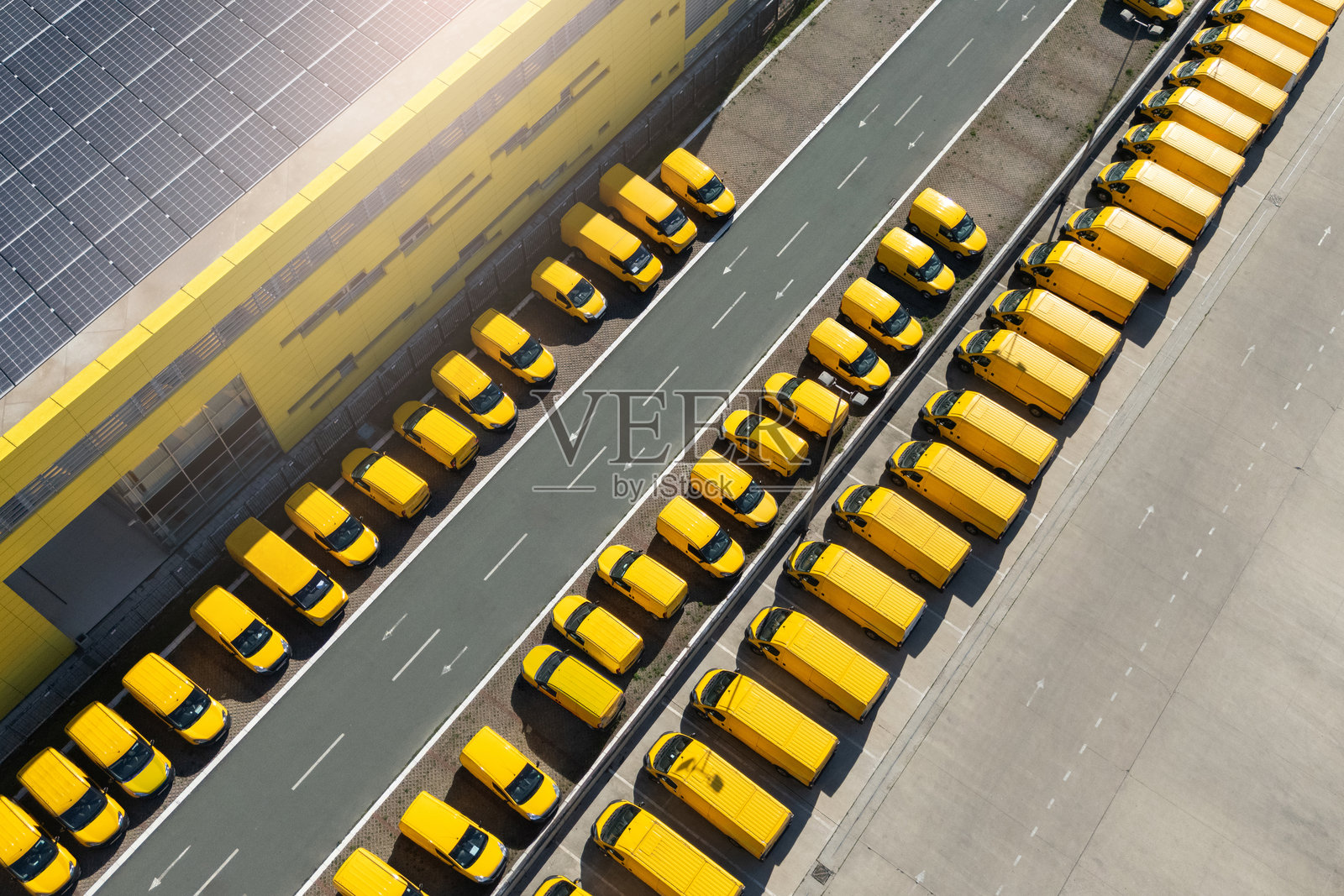 配送货车中心，屋顶上装有太阳能电池板。一队黄色邮政车辆。照片摄影图片