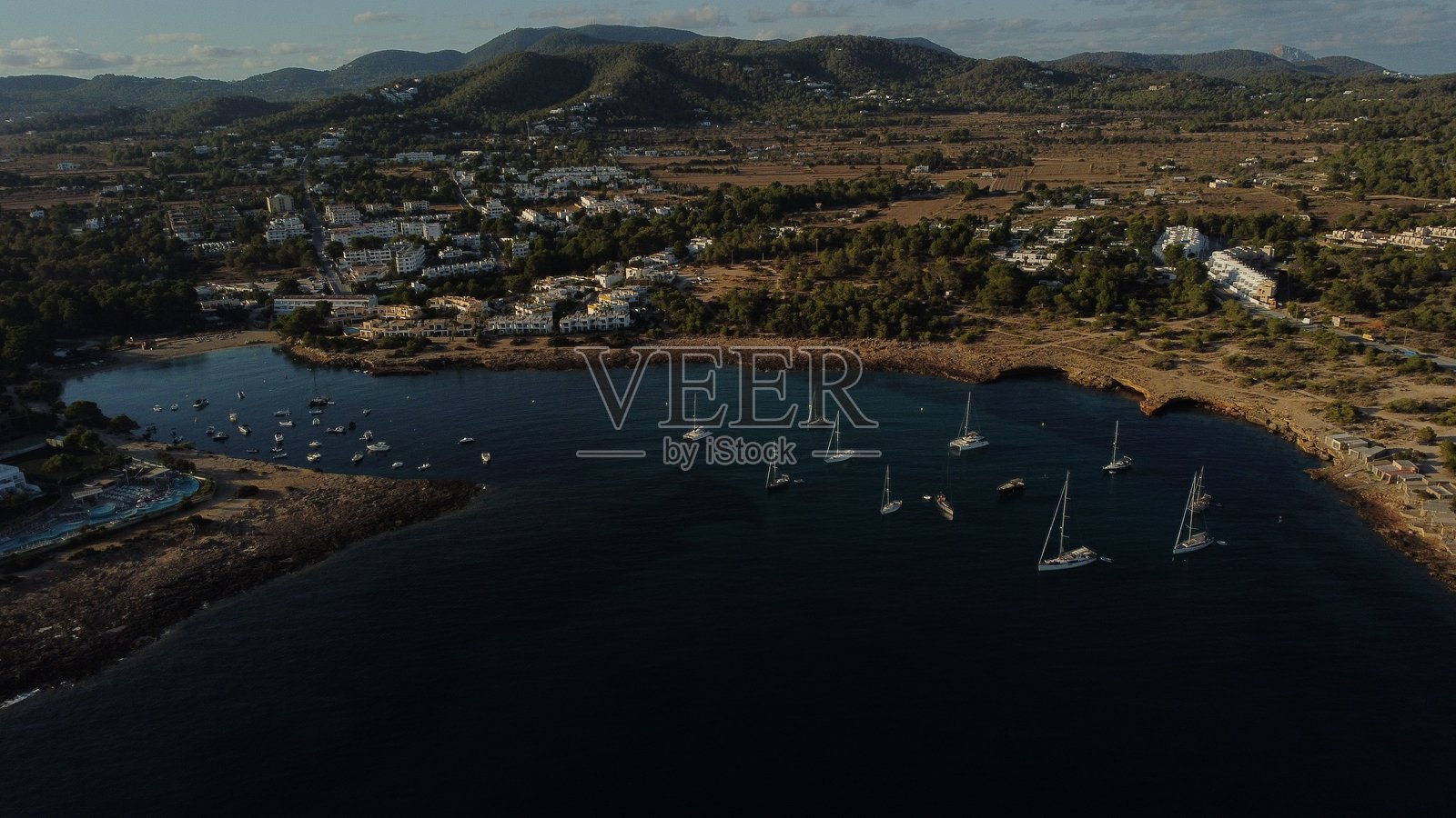 伊比萨岛岩石海岸附近停泊的船只的无人机视角照片摄影图片