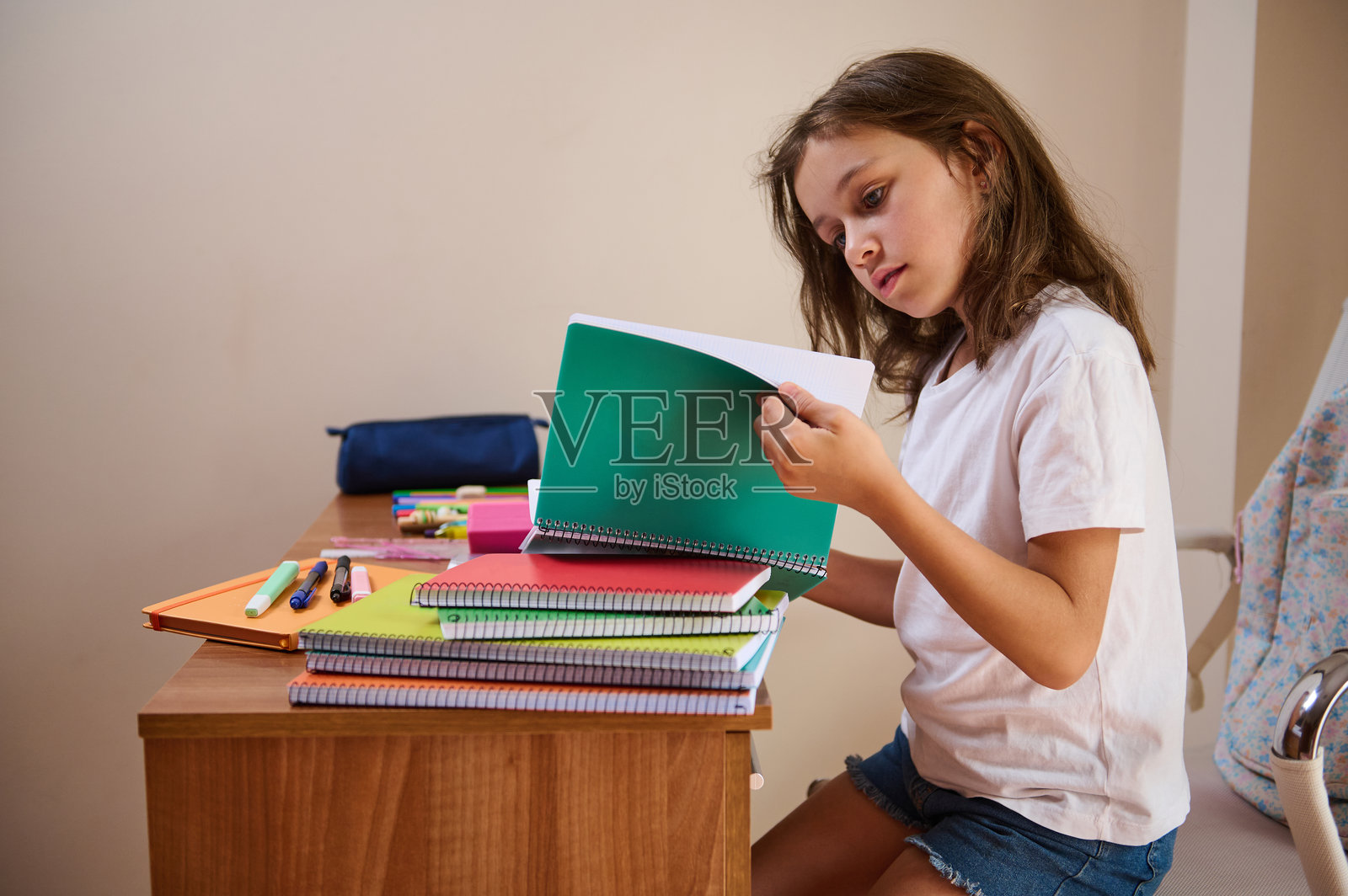 年轻女孩在书桌前学习，桌上有笔记本和文具照片摄影图片