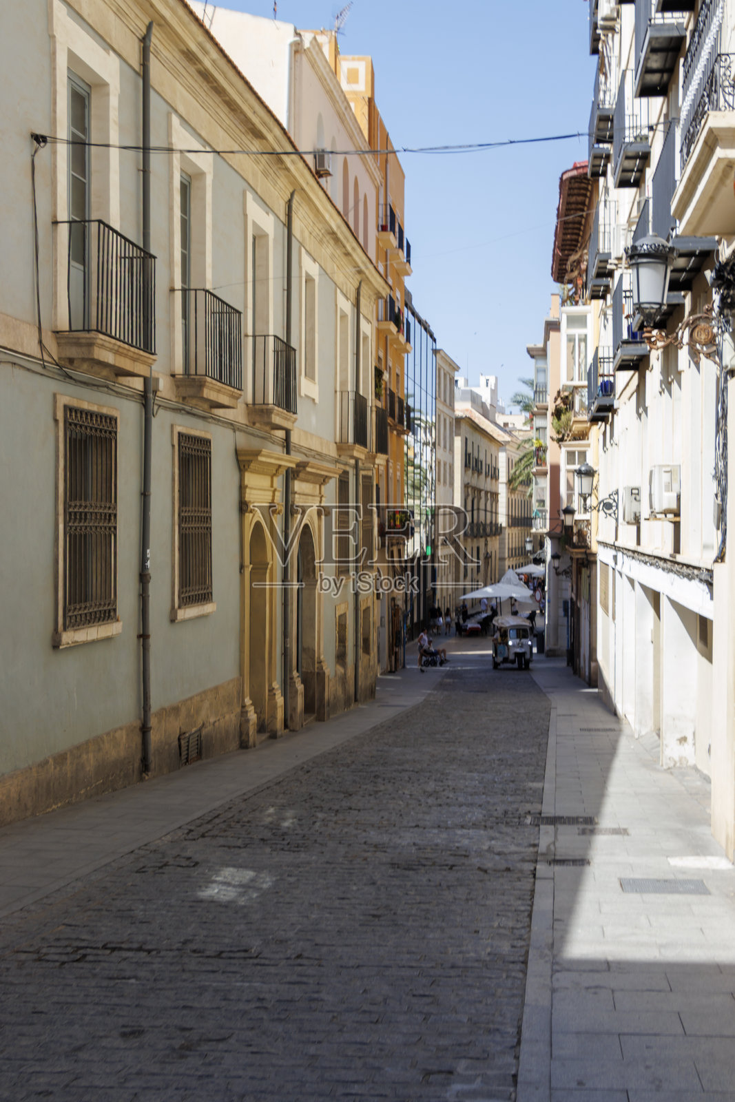 阿利坎特一条安静狭窄的街道,拥有保存完好的历史建筑,温暖的阳光和户外咖啡馆,邀请人们悠闲漫步。照片摄影图片