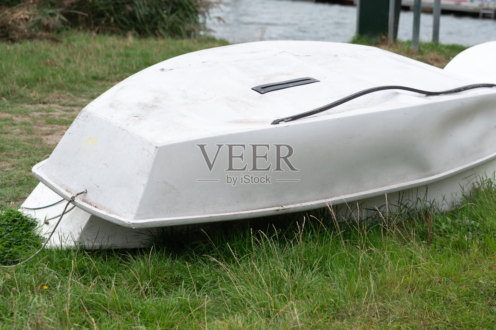 一只白色的船目前侧卧在浓密的草丛中。照片摄影图片