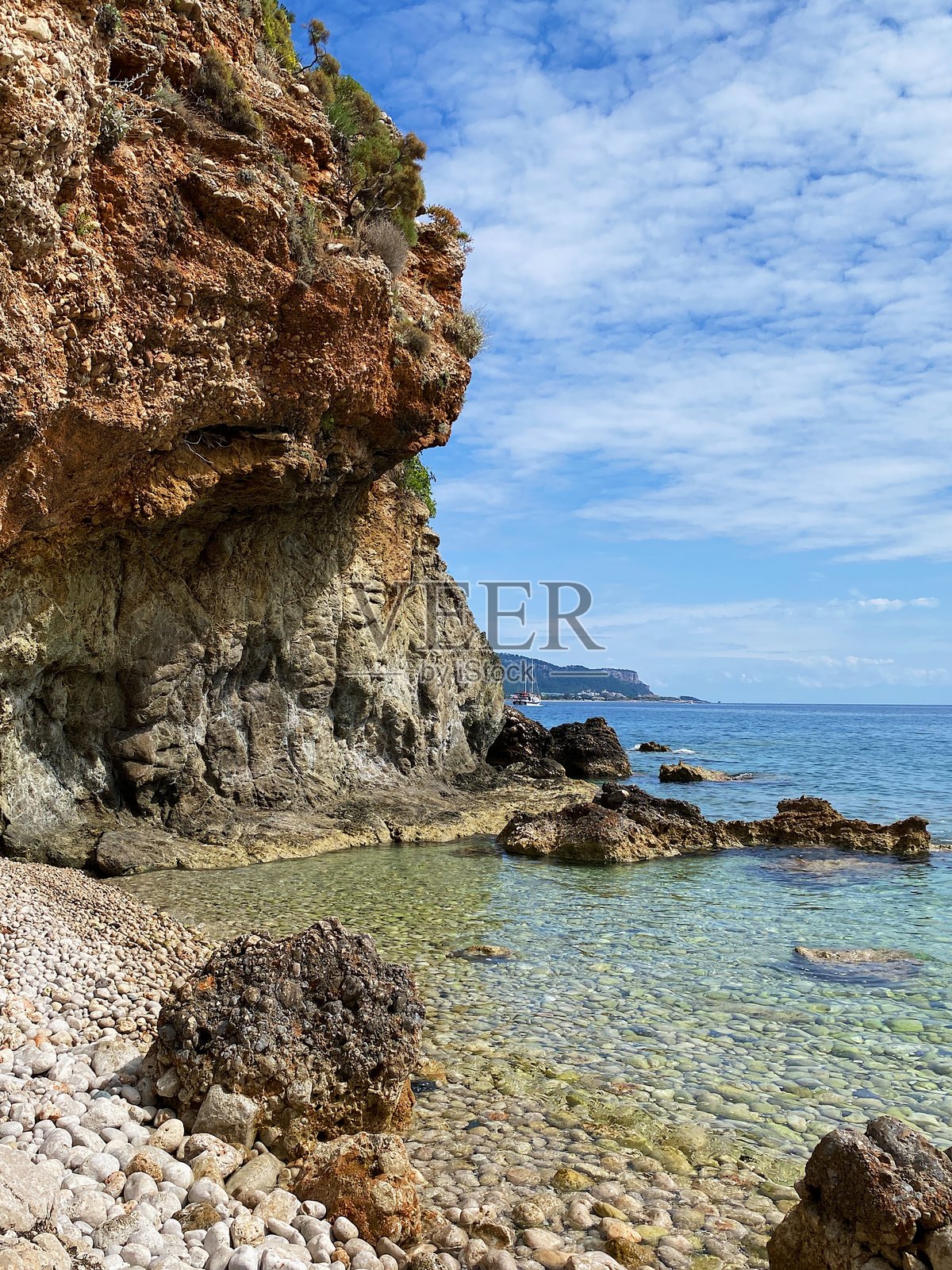 一个小海滩，白色的石头、岩石和清澈的蓝色地中海水，位于土耳其安塔利亚的凯梅尔，阳光明媚。小白湾。照片摄影图片