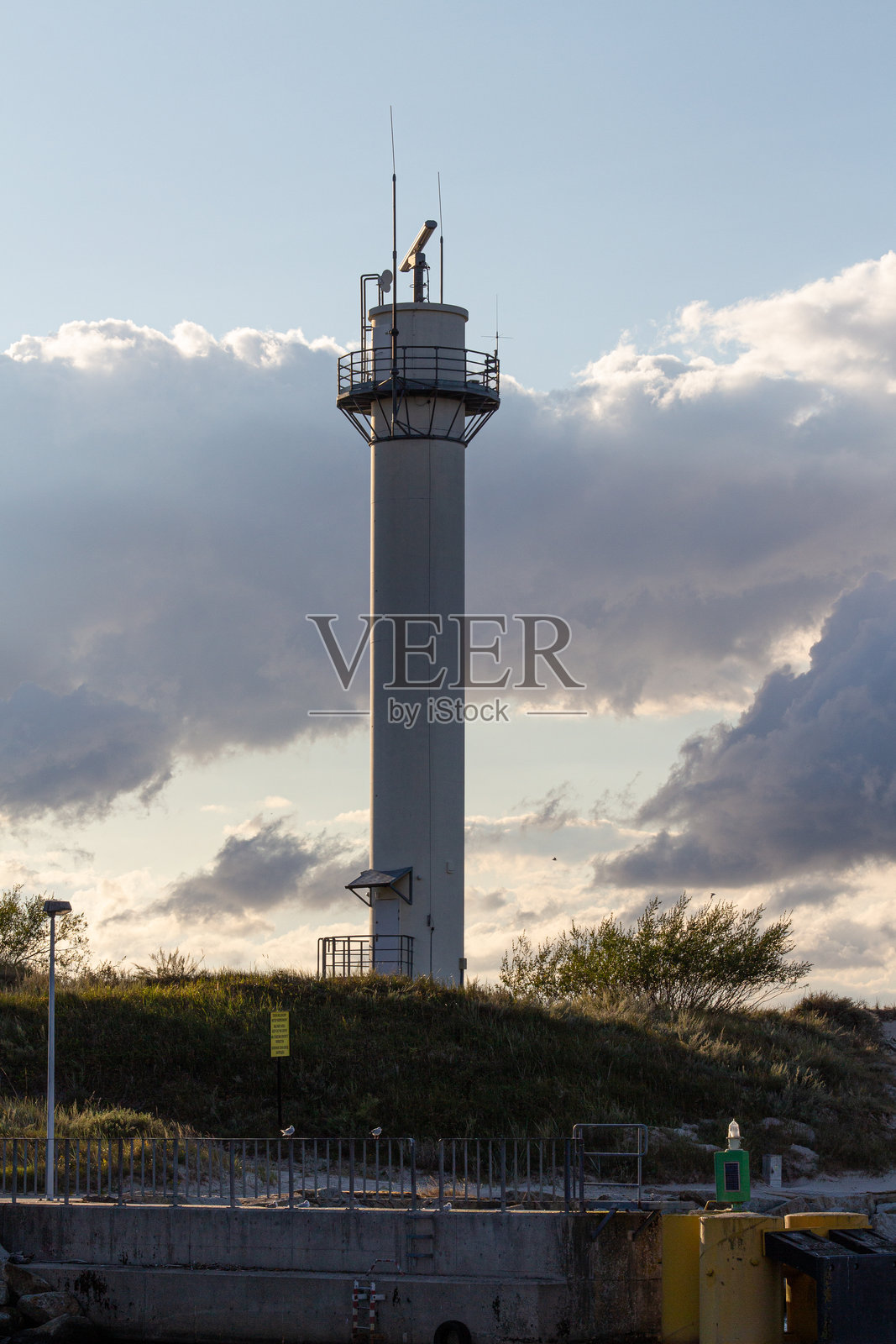 高耸的通信塔在傍晚的光线下，映衬着戏剧性的云朵。照片摄影图片