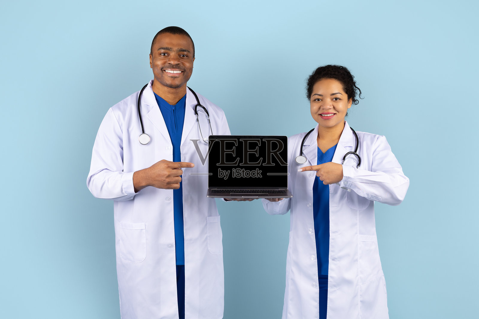 微笑的非裔美国医生在工作室指着笔记本电脑屏幕照片摄影图片