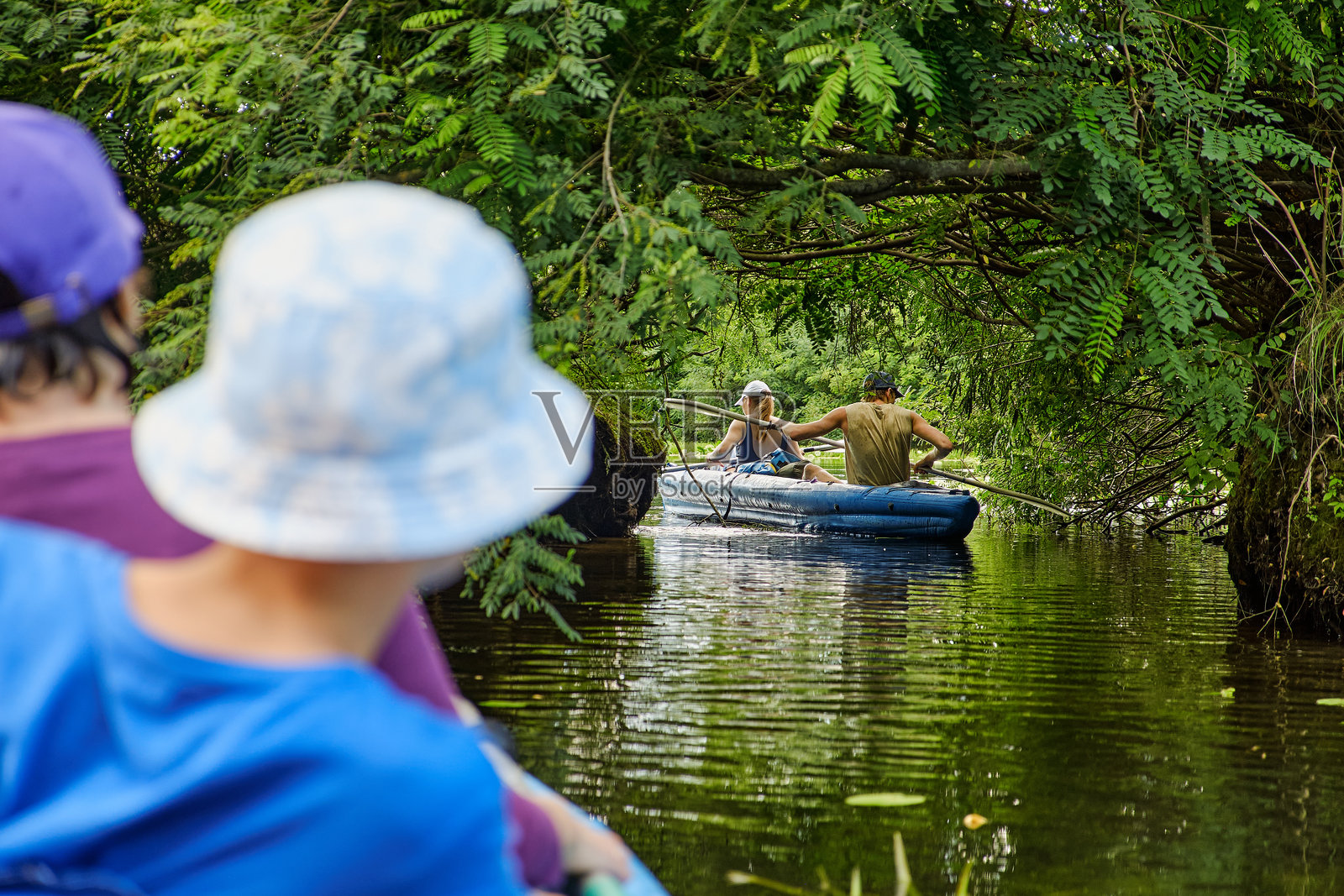 人们在宁静的河流上划皮艇，周围环绕着郁郁葱葱的树木。夏季自然中的冒险与户外娱乐。照片摄影图片