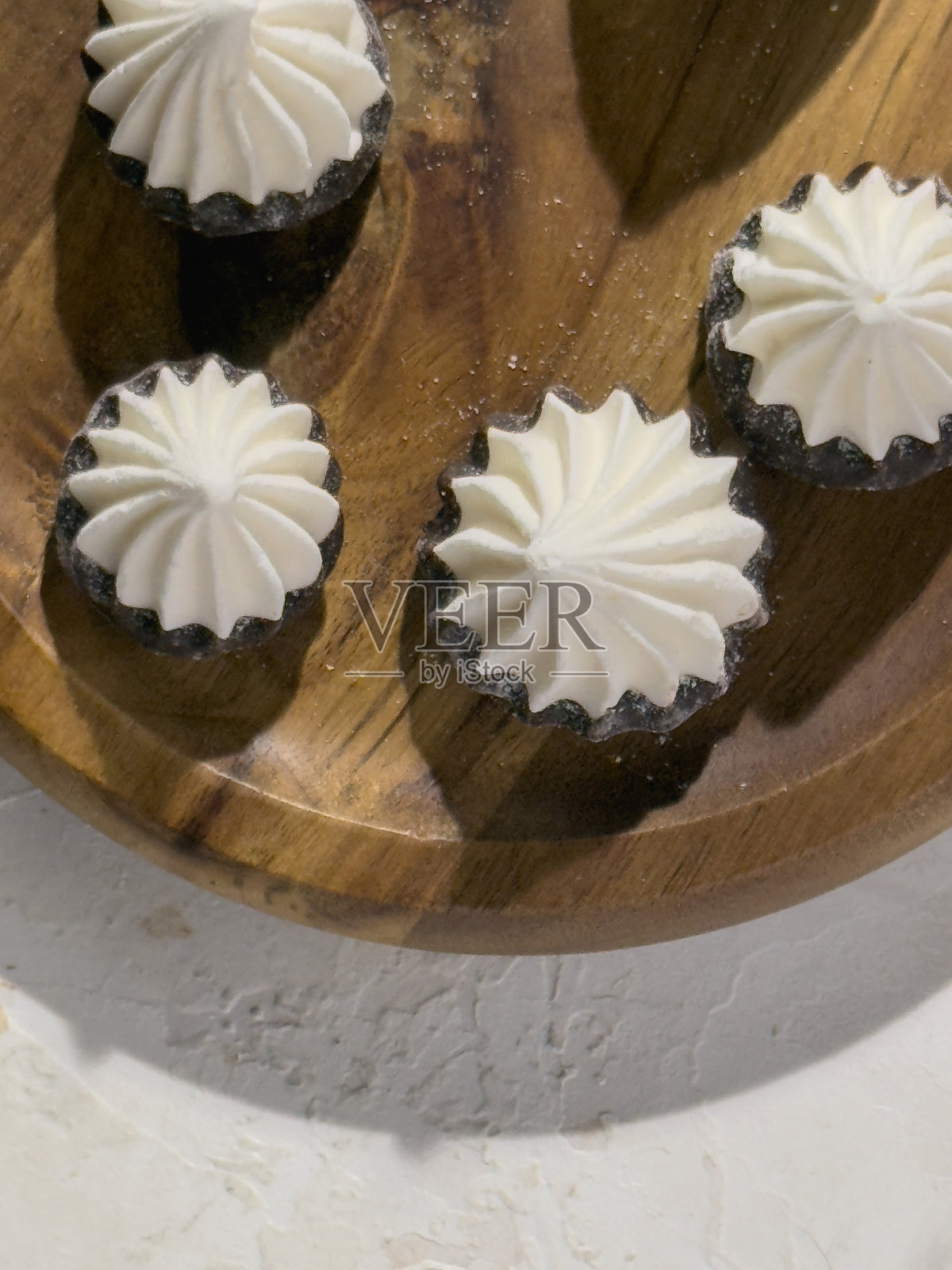 细致可口的甜蜜蛋白霜小点心特写，巧克力底座与其风味和口感相得益彰。照片摄影图片