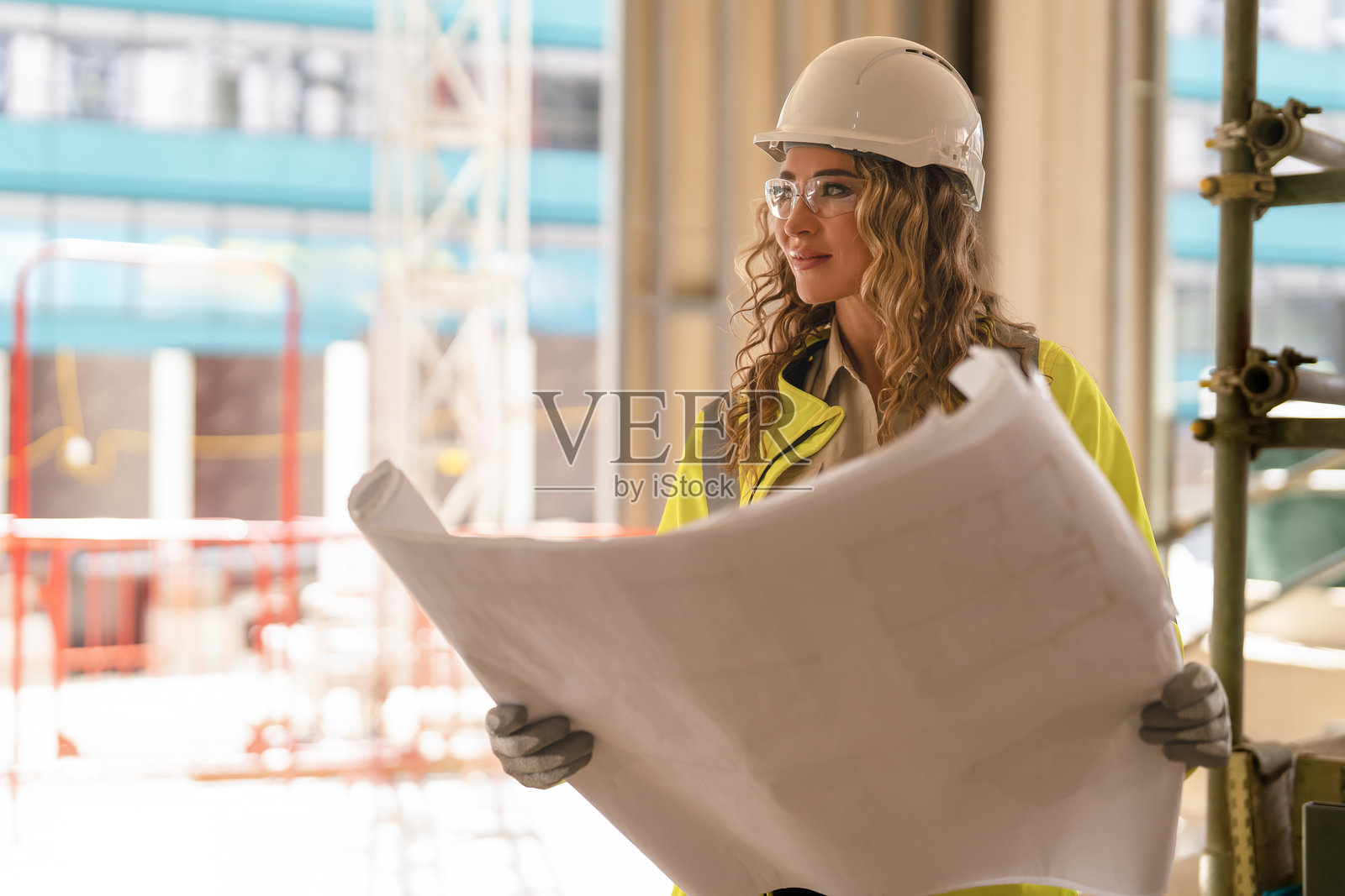 女性建筑工人在施工现场查看蓝图以检查工作进度照片摄影图片