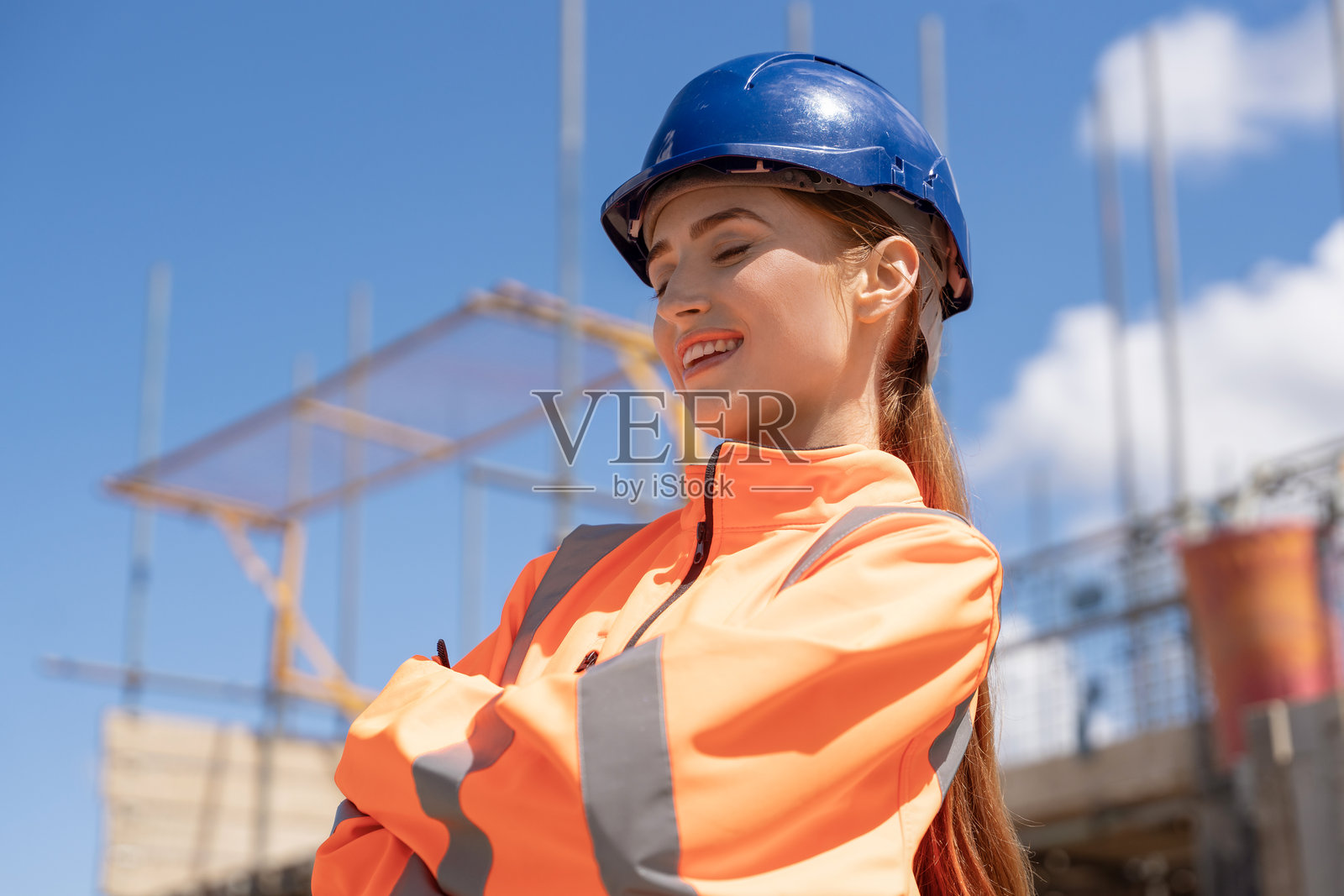 年轻女建筑工人在施工现场穿着明亮的安全反光夹克进行工作照片摄影图片