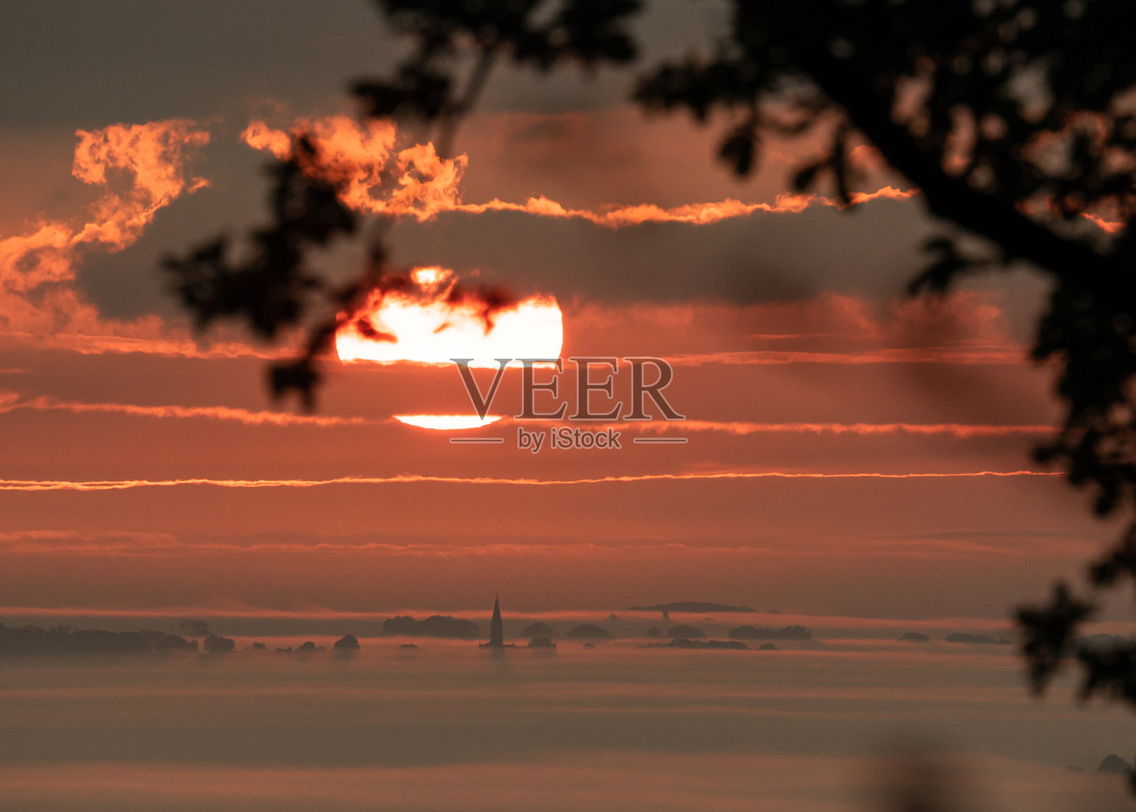 雾蒙蒙的早晨日出，天空中可见巨大的太阳。背景中教堂的轮廓勾勒出一幅如画的氛围景观。照片摄影图片