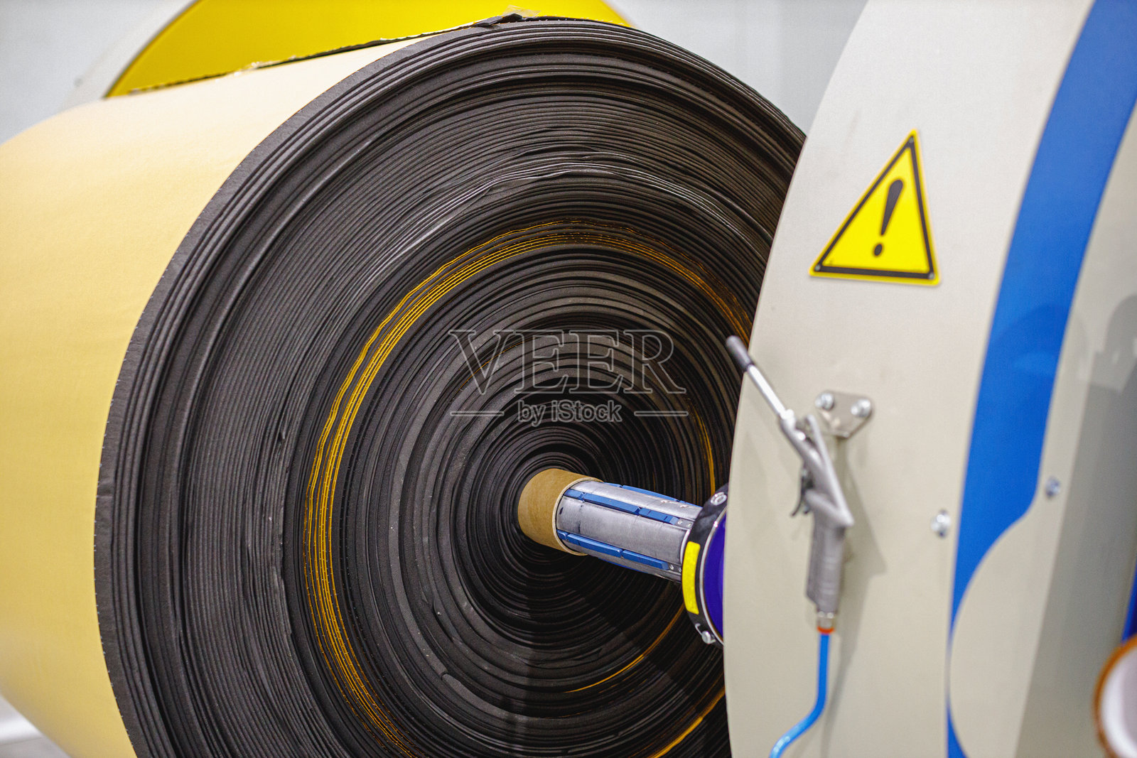 制造设施中带有安全警告的大型机器上的工业卷绕卷照片摄影图片