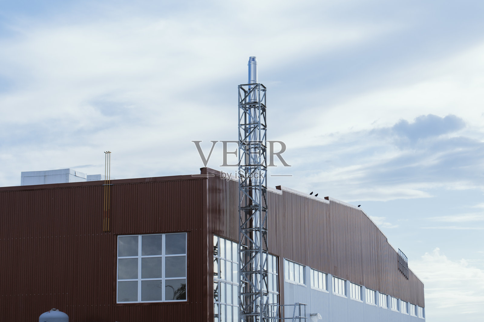 现代工业设施外观，特色红白相间的金属面板外立面和银色排气或通风管道。概念现代工业建筑。照片摄影图片