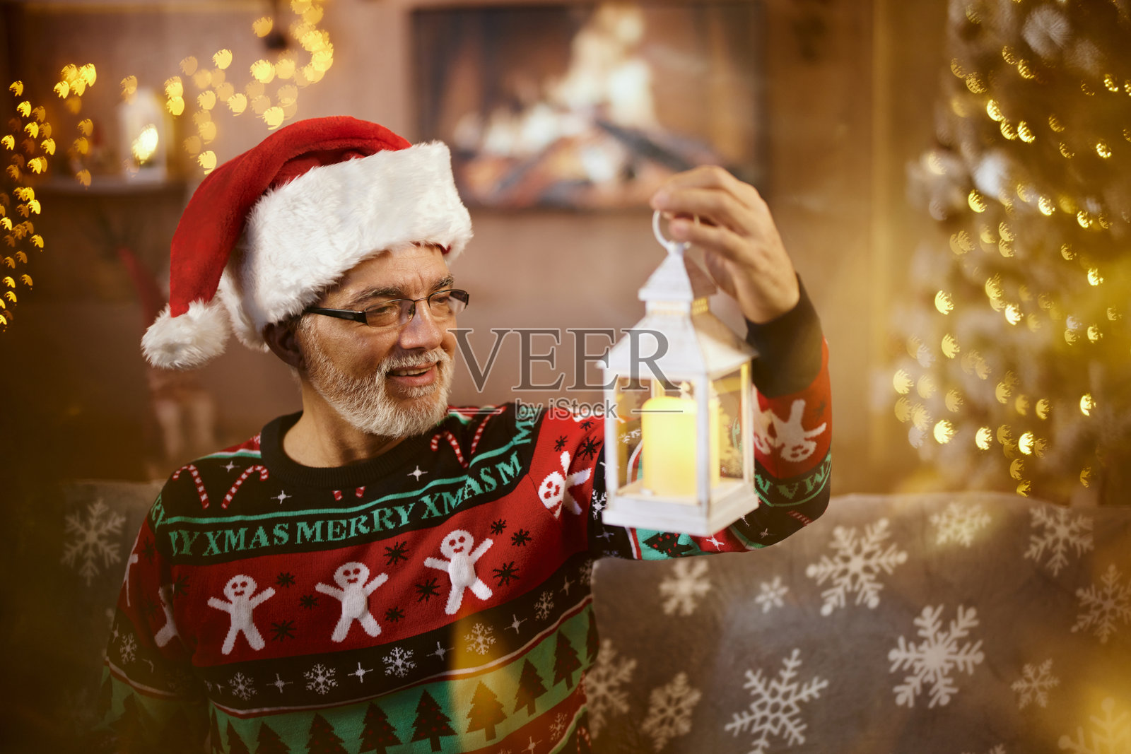 快乐的老年人在家中拿着圣诞灯笼。照片摄影图片