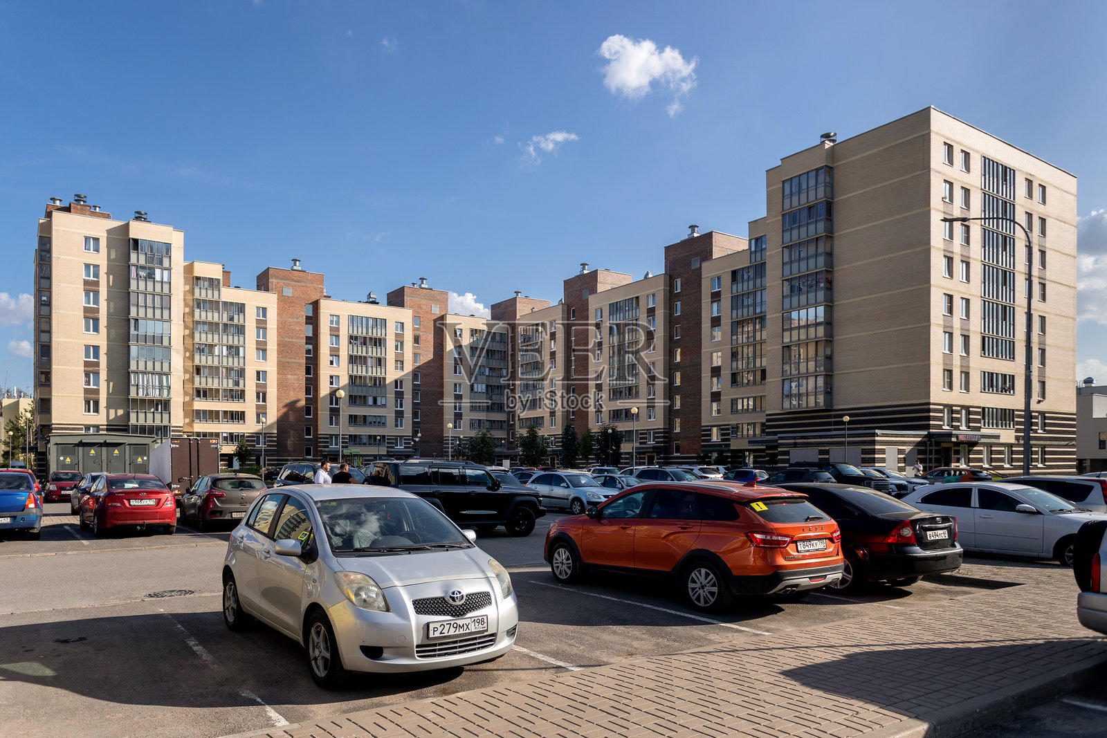 俄罗斯圣彼得堡。住宅综合体“Zhivi! V Kurortnom”。大型多层住宅楼前的停车场里停满了汽车。照片摄影图片