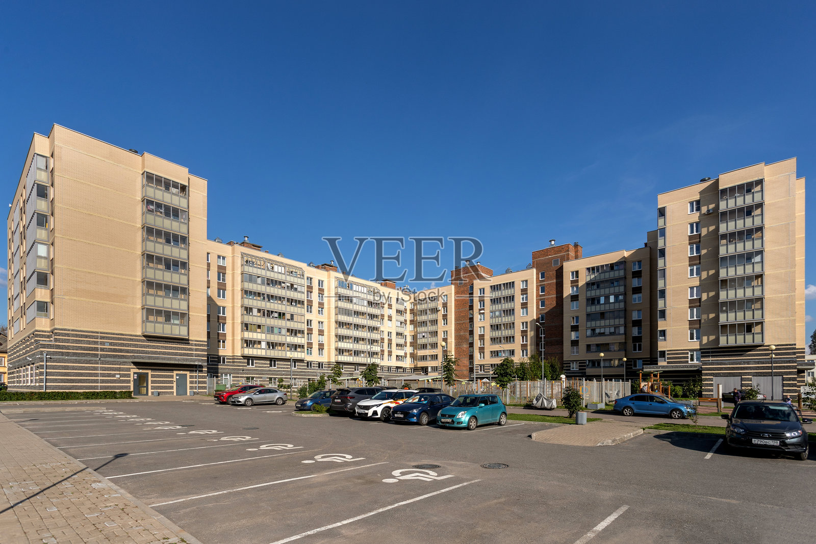 俄罗斯圣彼得堡。住宅综合体“Zhivi! V Kurortnom”。大型多层住宅楼前的停车场里停满了汽车。照片摄影图片