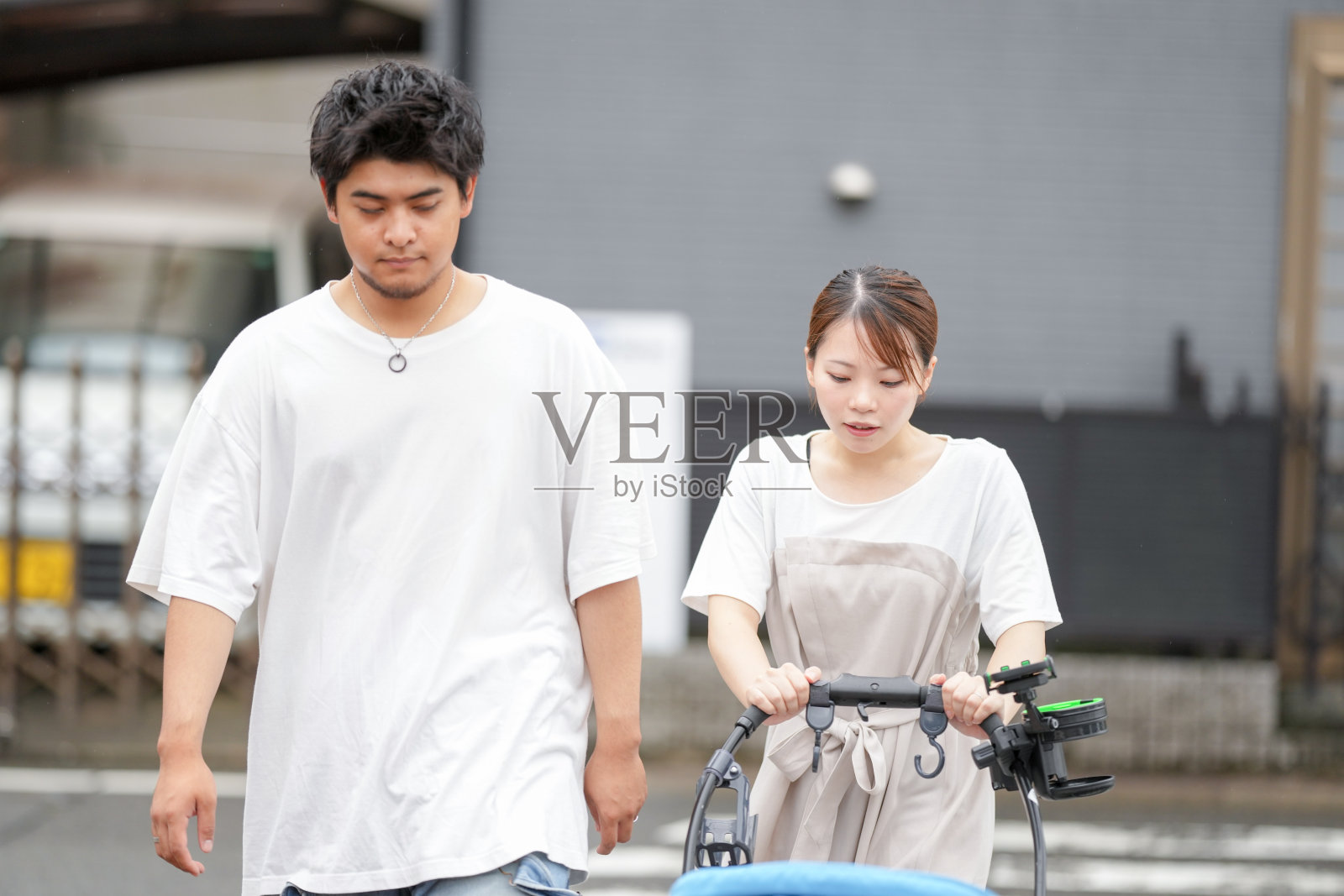 一男一女推着婴儿车在街上散步照片摄影图片