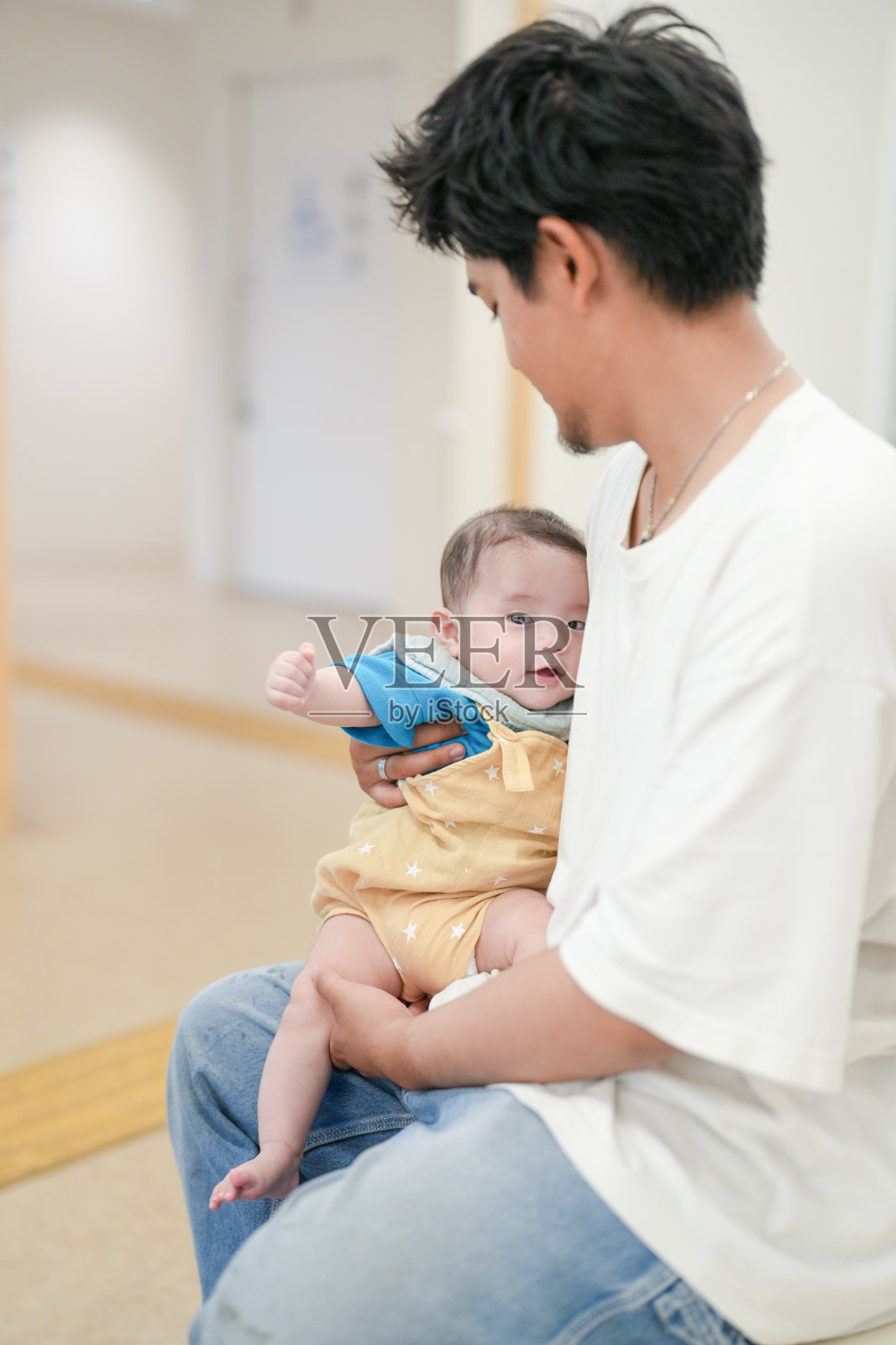 一个男人抱着一个婴儿。照片摄影图片