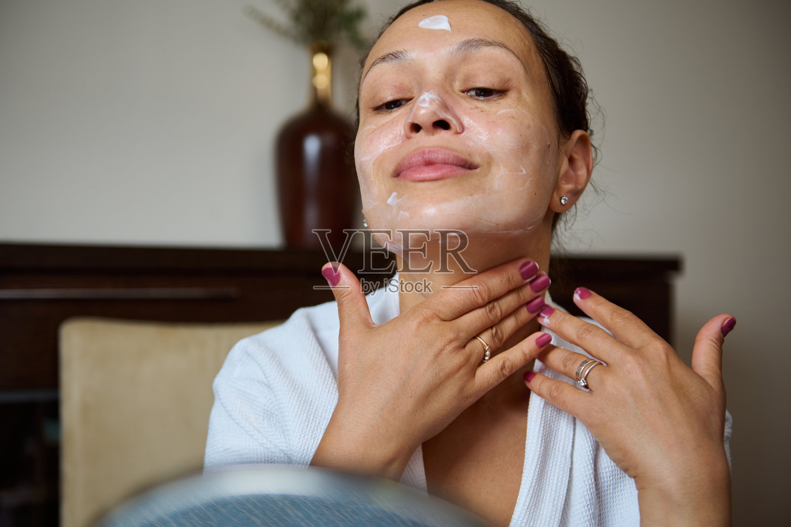 女性在家中进行护肤程序时涂抹面霜照片摄影图片